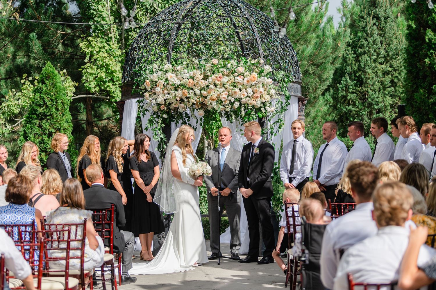 Wedding ceremony guests gathered outdoors in a garden setting at Sleepy Ridge, a Utah County wedding venue.
