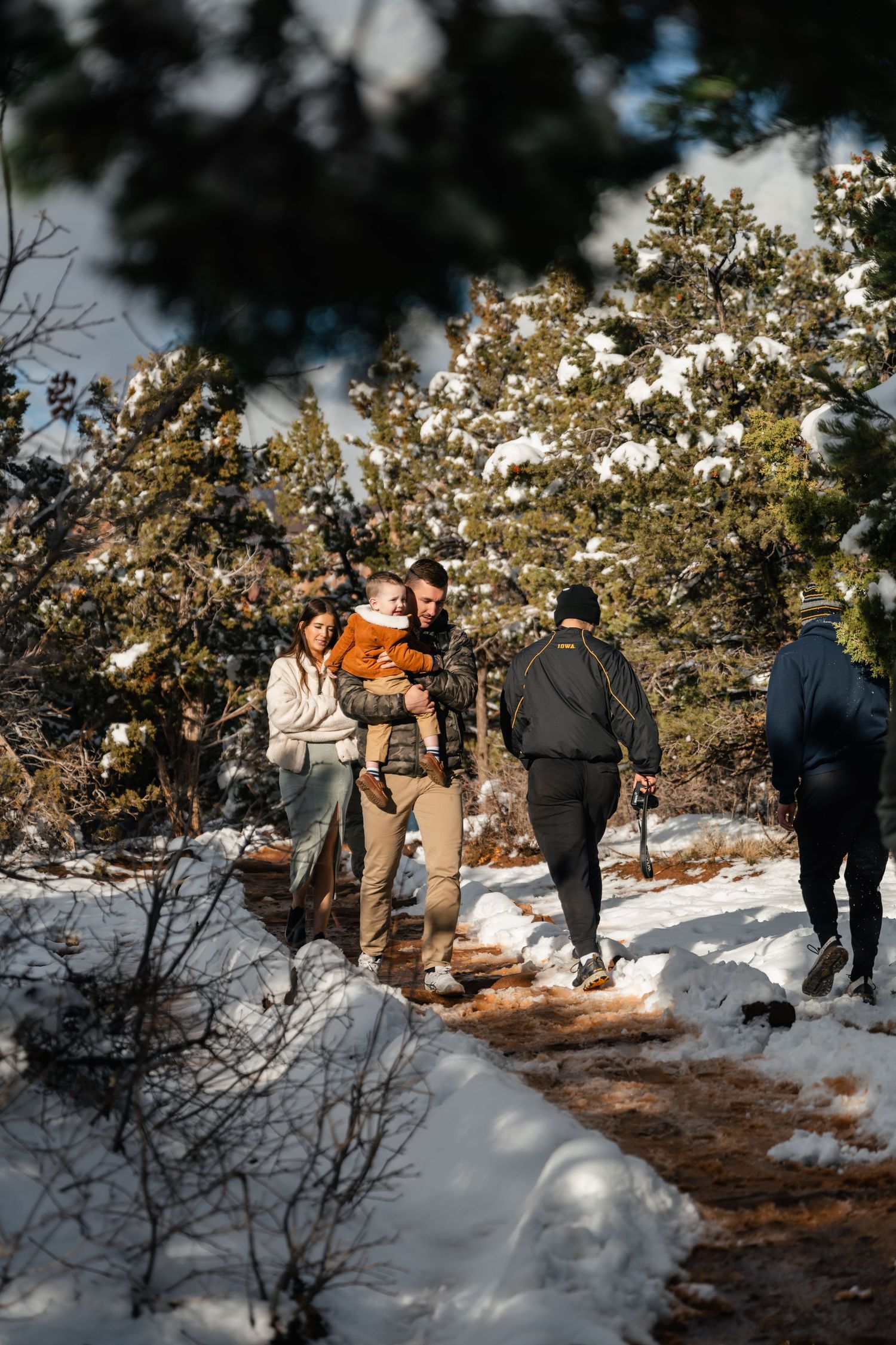 A group walks along a snowy hiking trail through winter wilderness.