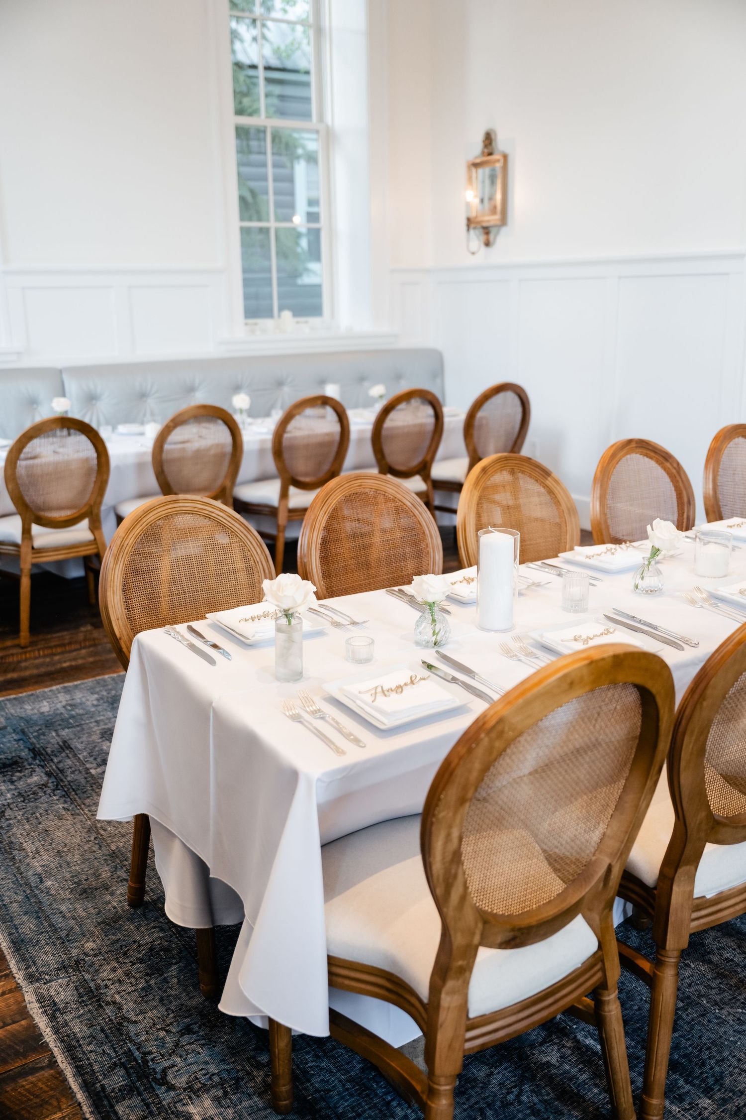 Elegant restaurant interior with round-backed wooden chairs and white-clothed tables set for fine dining.