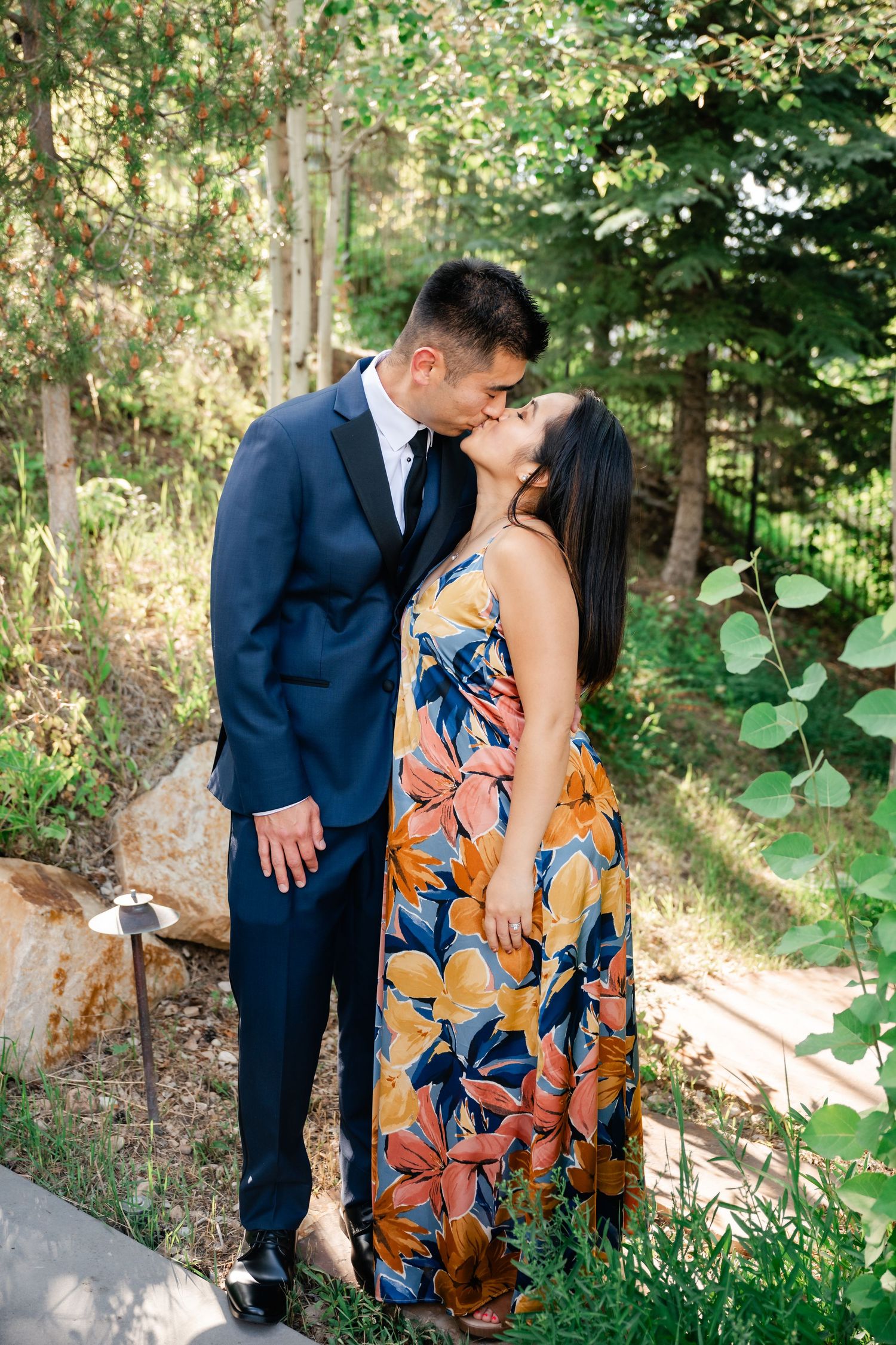 A couple in formal attire sharing a romantic moment in a garden setting.