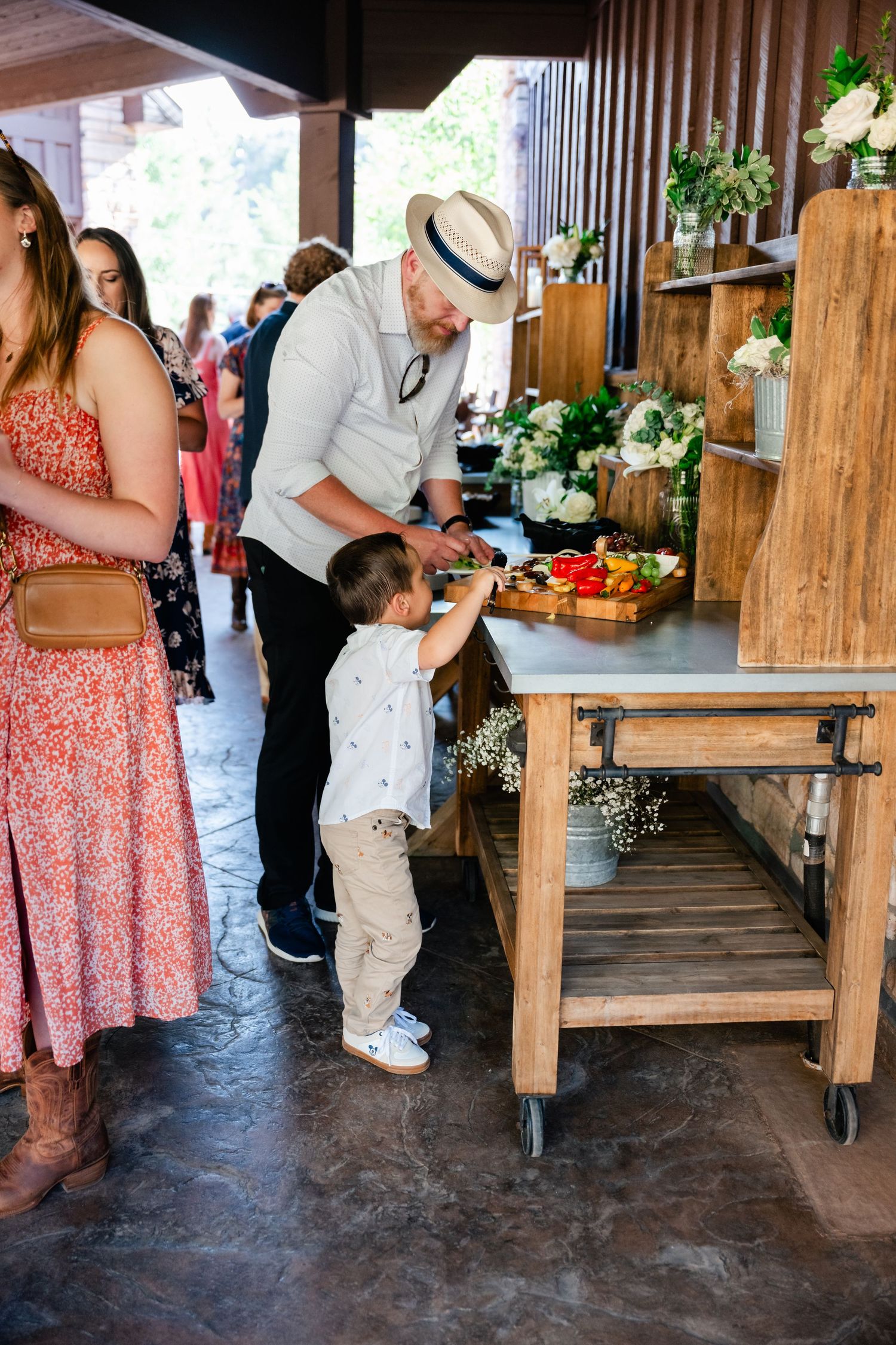 A rustic wedding reception buffet table with fresh flowers and wooden decor.