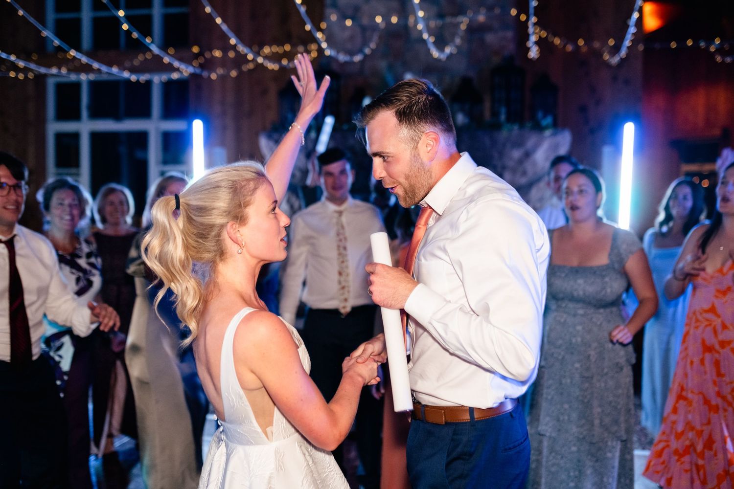 Wedding reception dance floor lit with string lights and blue ambient lighting.