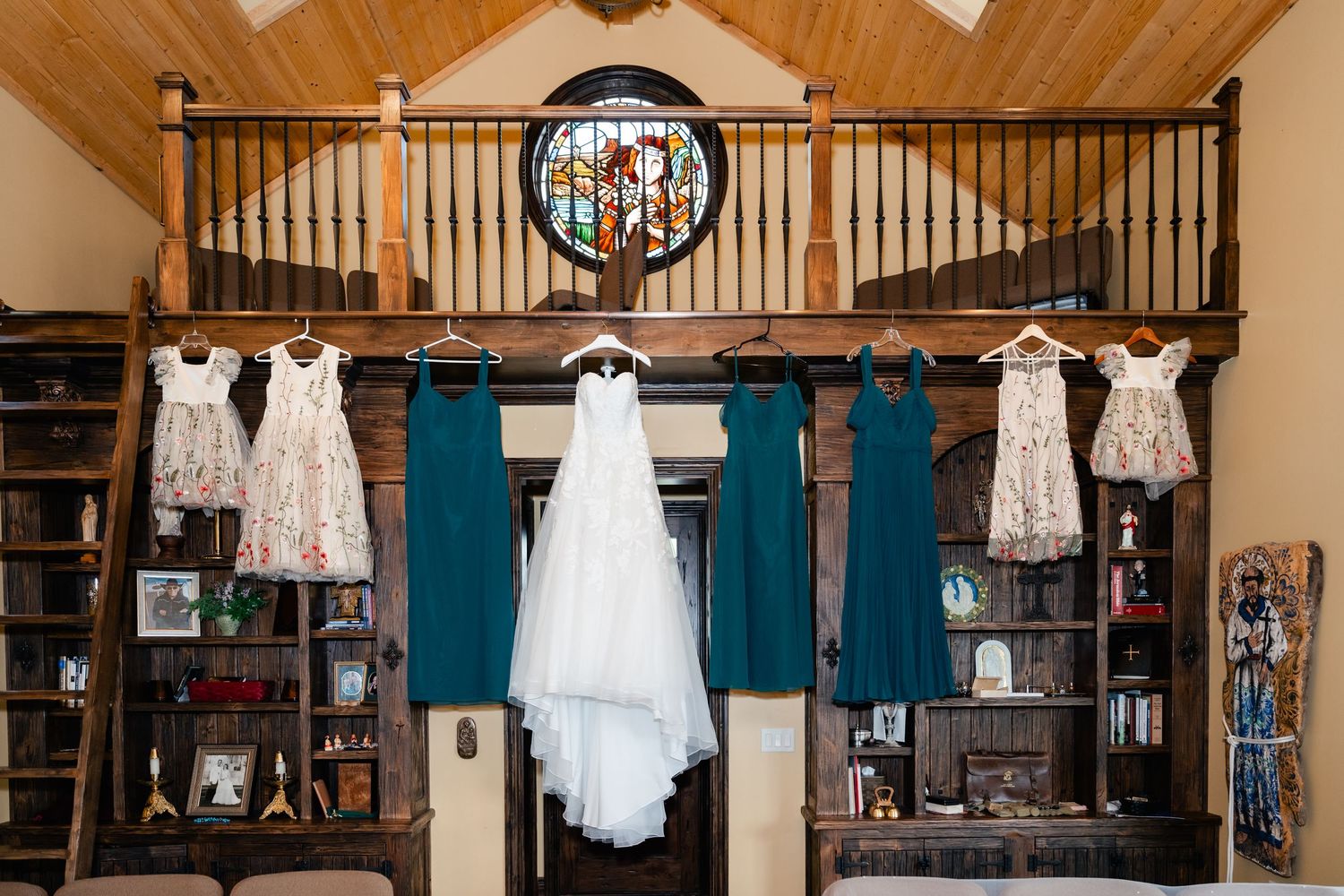 Wedding dresses and formal attire hanging from wooden beams in a rustic venue.