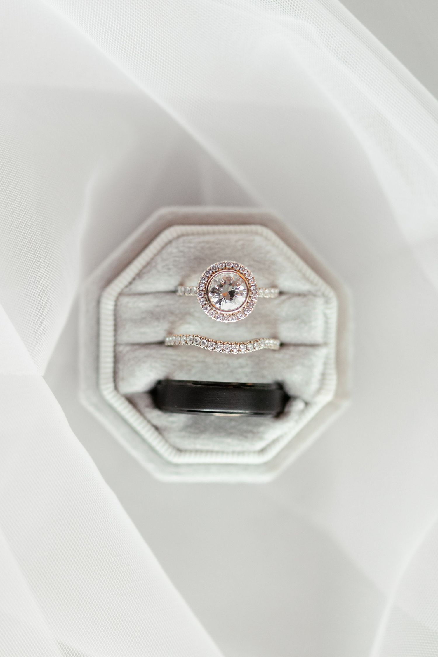A delicate rose gold engagement ring with a round center stone and halo design displayed in a white ring box.