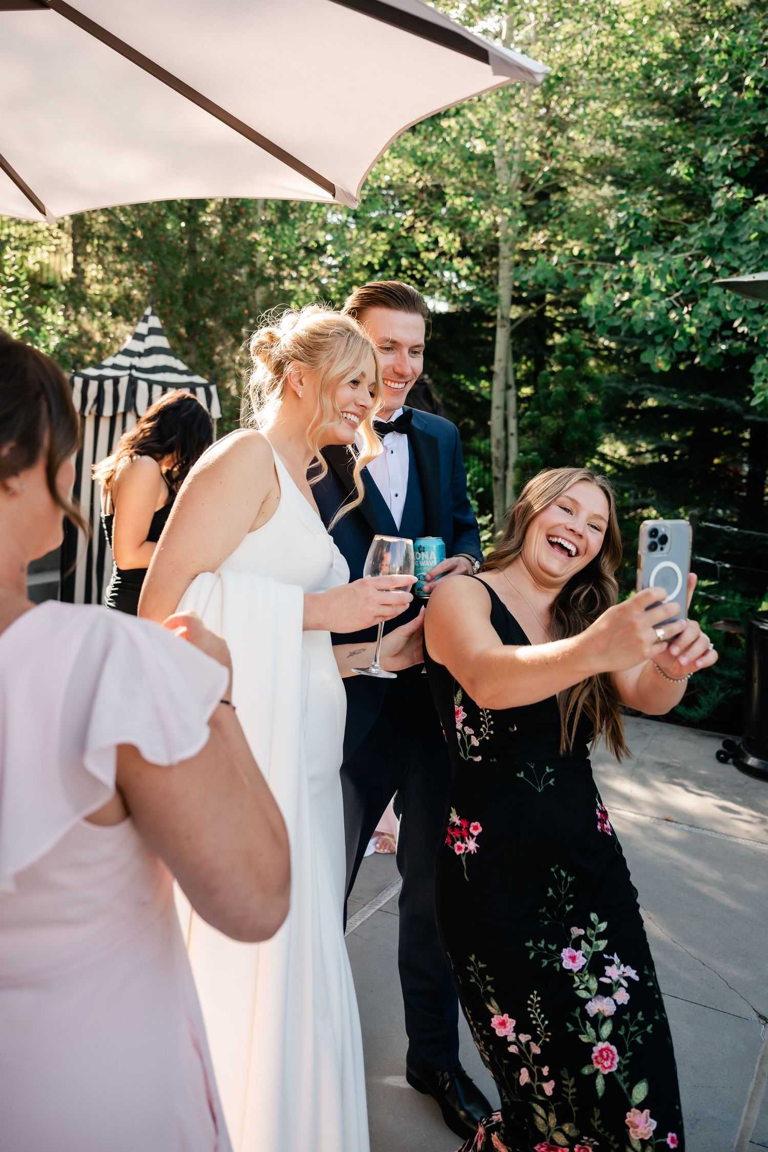 Wedding guests share joyful moments and take photos under outdoor canopy.
