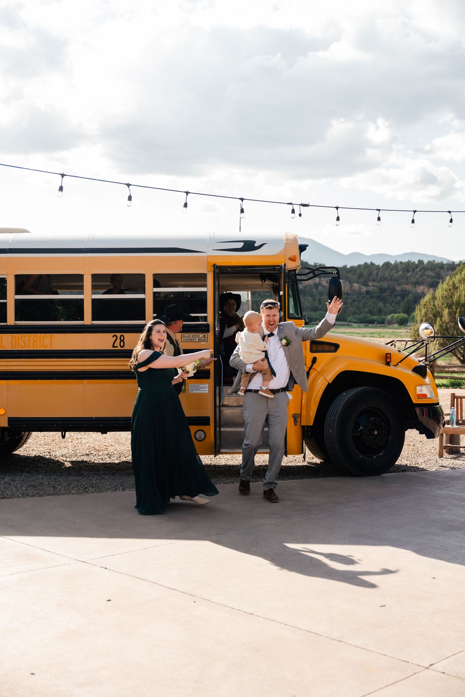 A yellow school bus parked at an outdoor venue with string lights overhead.