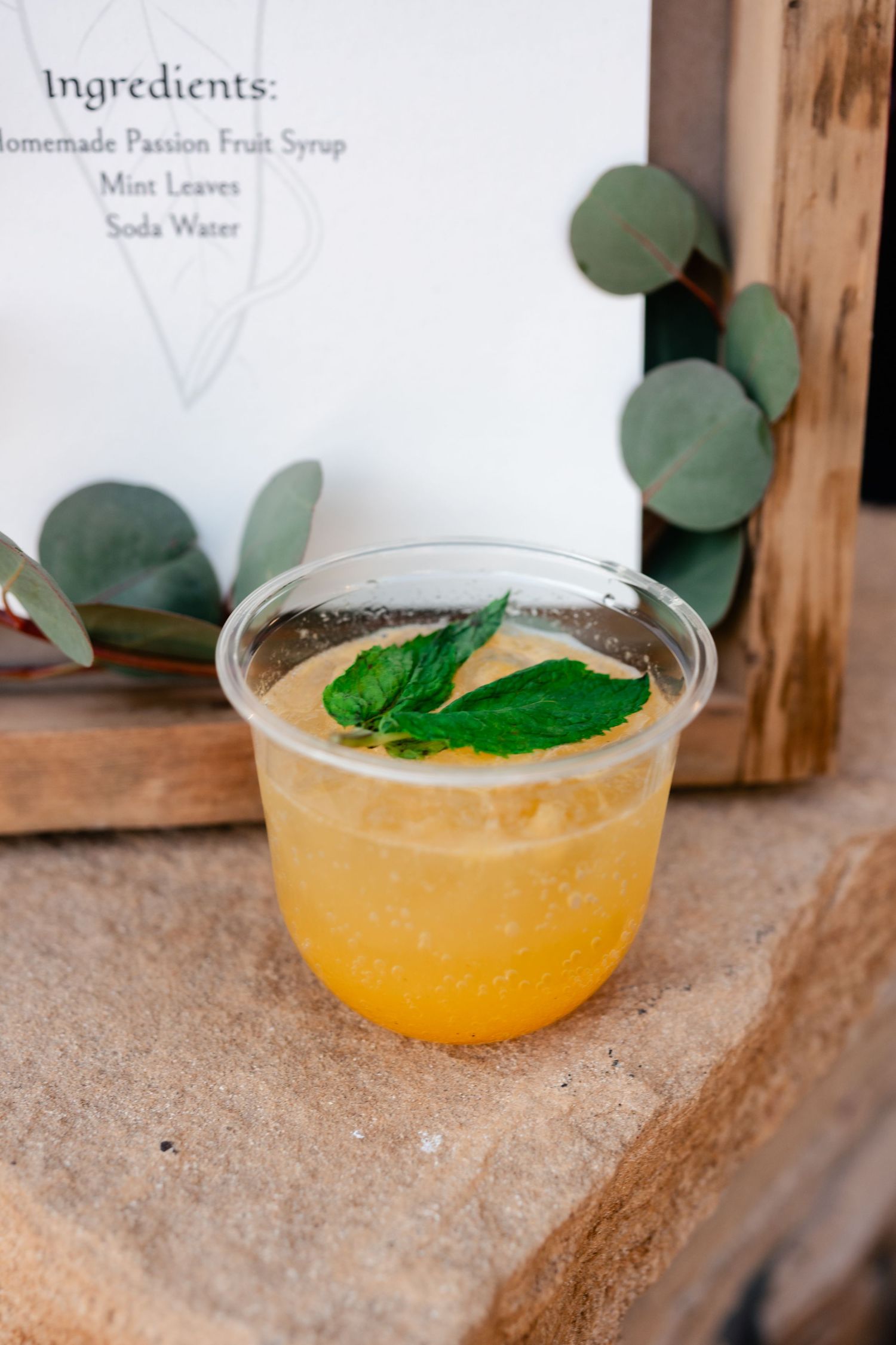 Orange cocktails garnished with fresh mint leaves are displayed on a wooden surface.