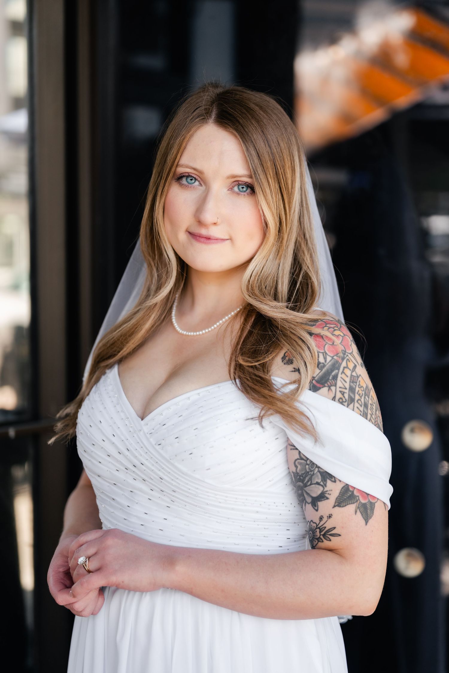 A bride in a white sweetheart neckline dress poses with natural window lighting.