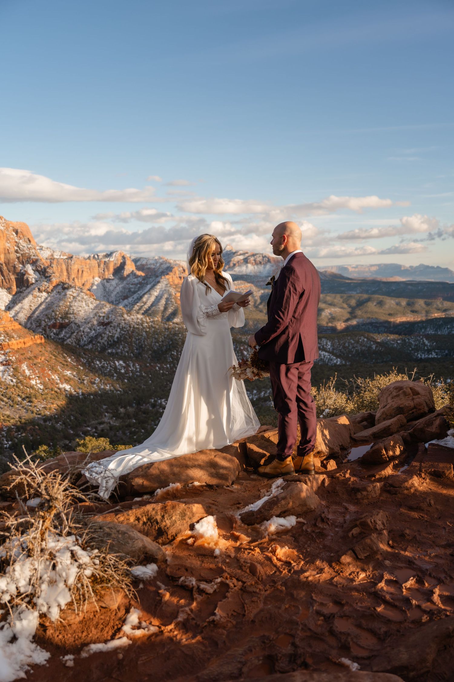 Couple enjoying sunset views from a red rock overlook with snow-capped mountains in the distance.