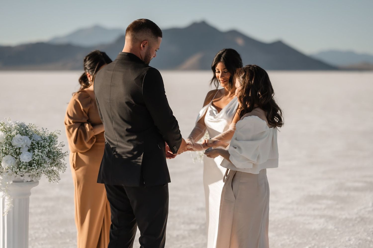 An intimate wedding ceremony unfolds against the backdrop of a vast salt flat desert landscape.