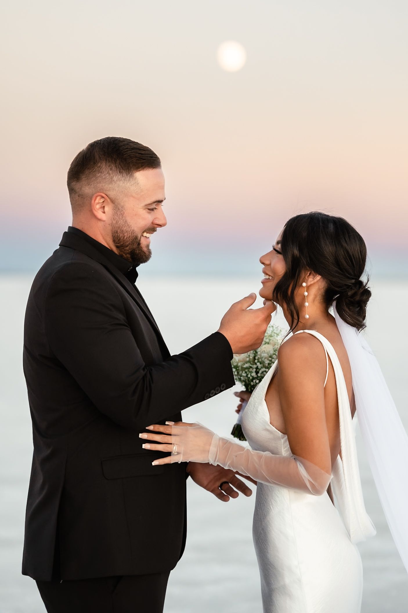 Emotional wedding moment captured between couple on salt flats during sunset.