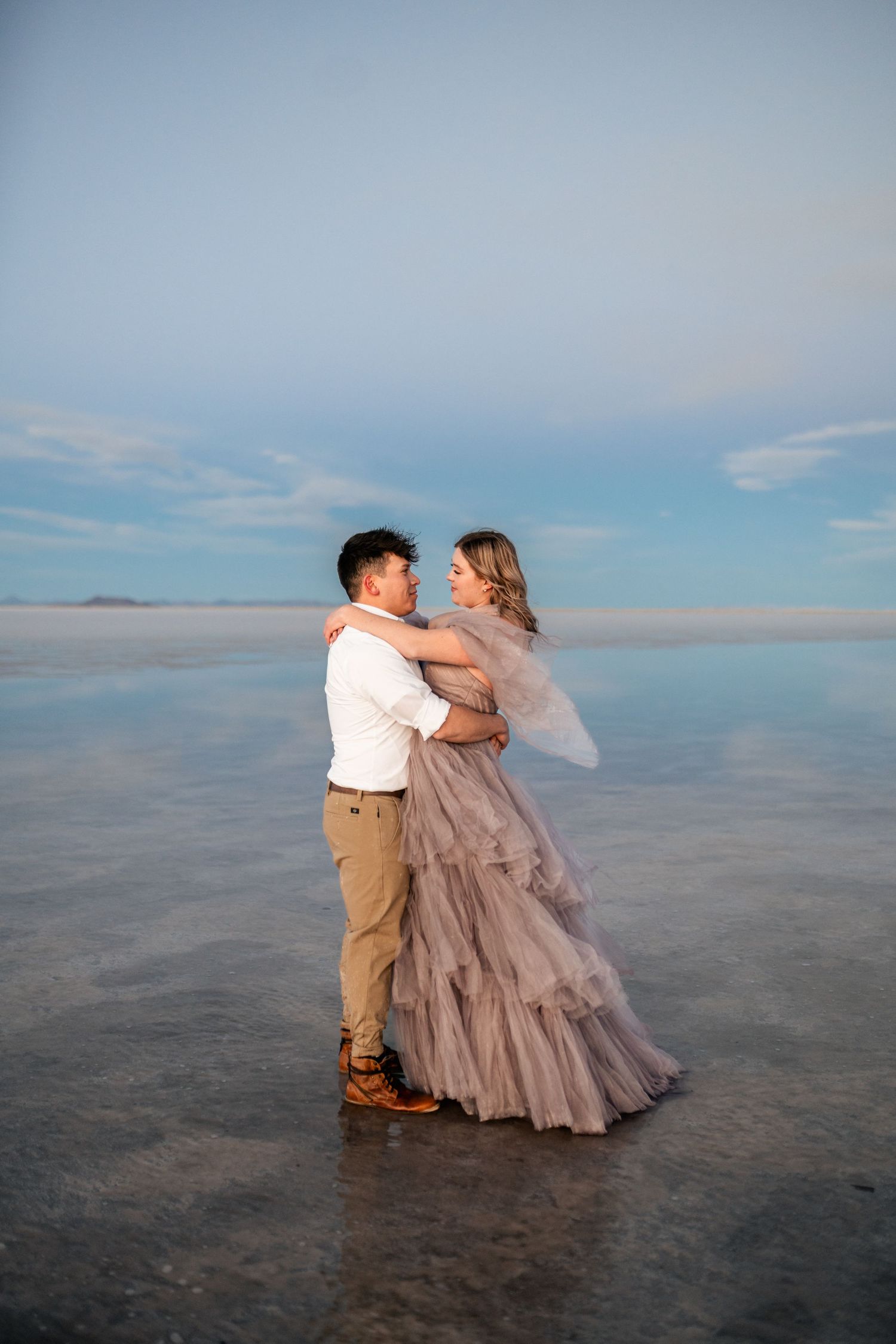 Romantic moment captured as the couple embraces amidst the serene beauty of the flooded Salt Flats during blue hour