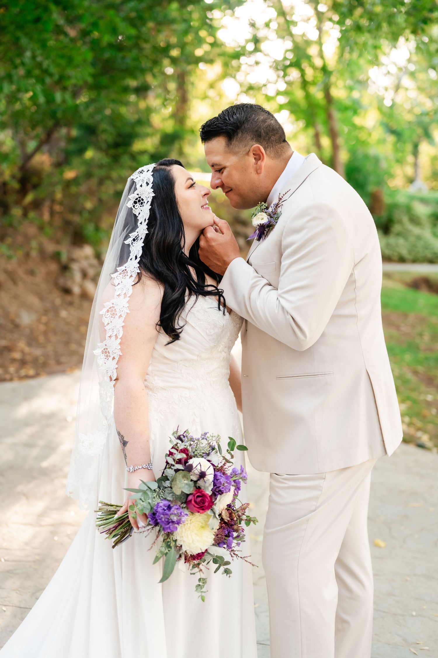 A romantic wedding moment captured outdoors with a beautiful floral bouquet featuring purple and white blooms.