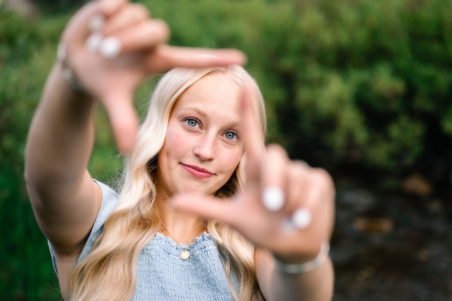 senior girl uses her hands to frame her face for a senior portrait