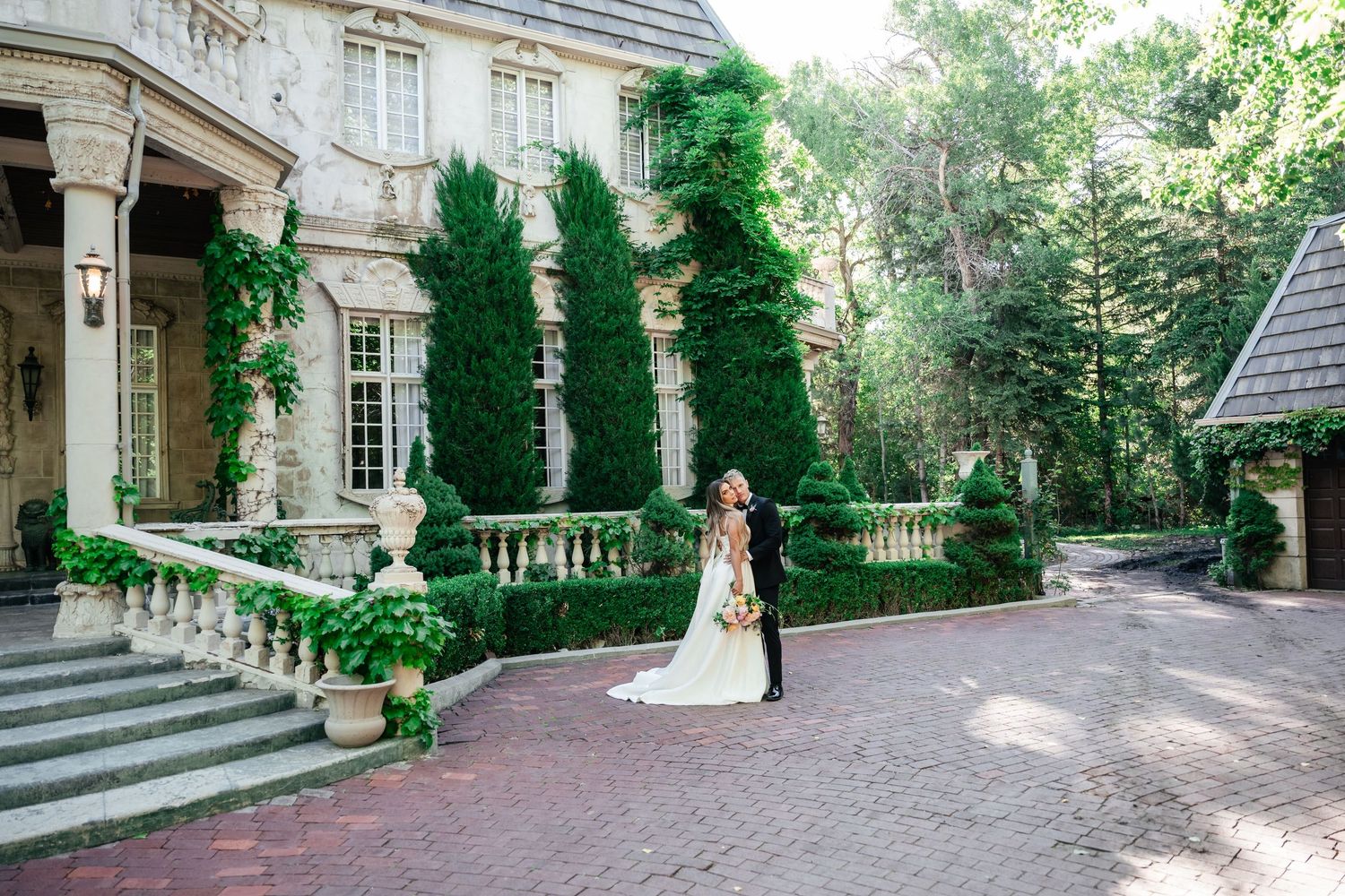 Wedding ceremony at an elegant stone mansion with ivy-covered walls and garden pathways.