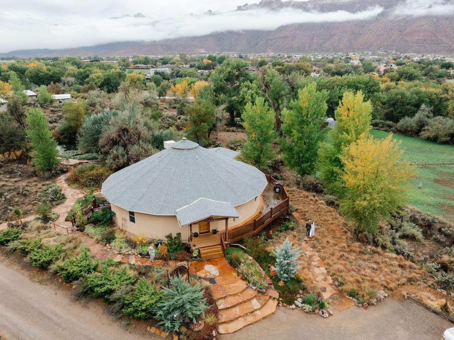 Aerial view of a luxury yurt retreat nestled in desert landscape with mountains and autumn trees.