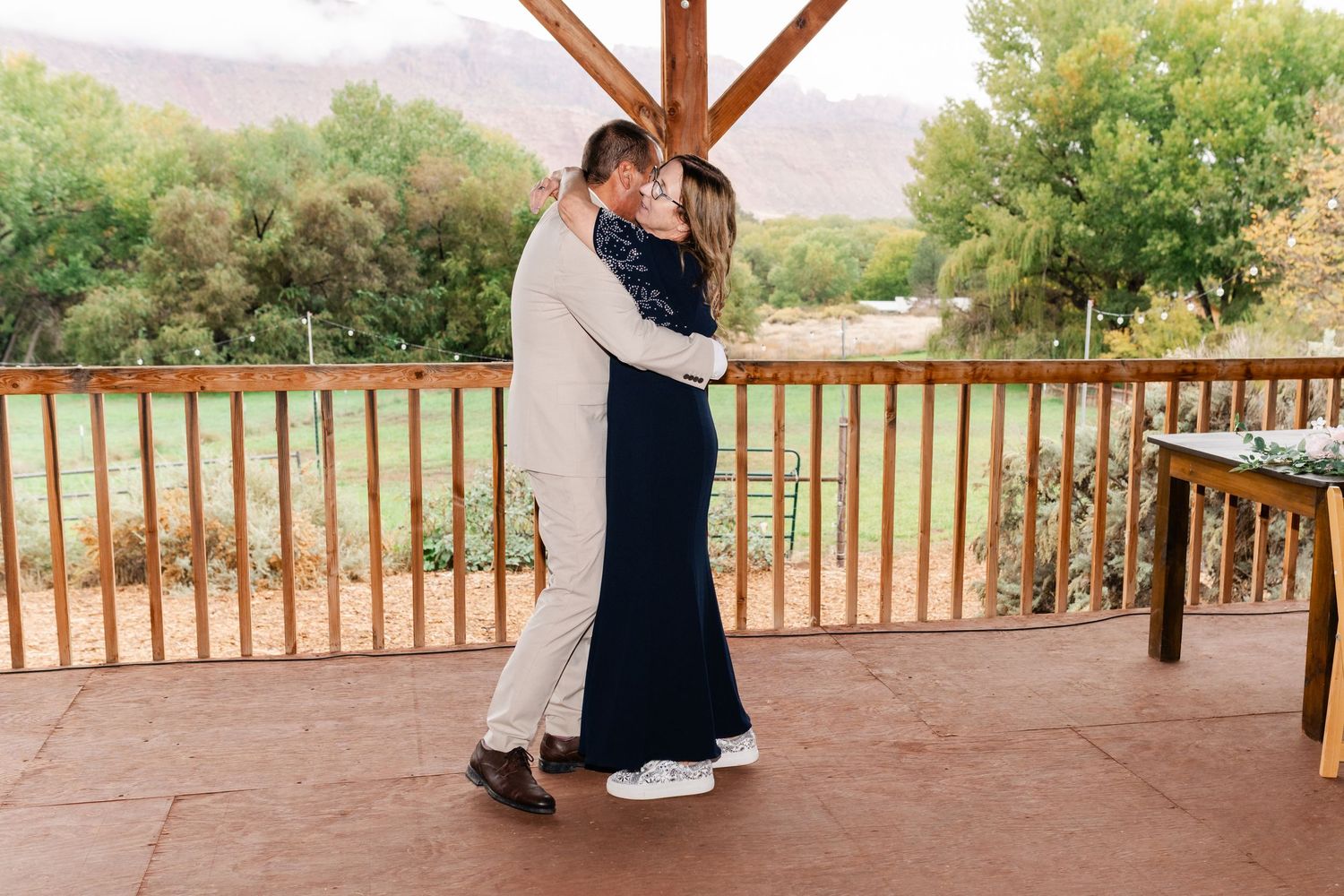 Wedding celebration on a rustic wooden deck overlooking a desert landscape.