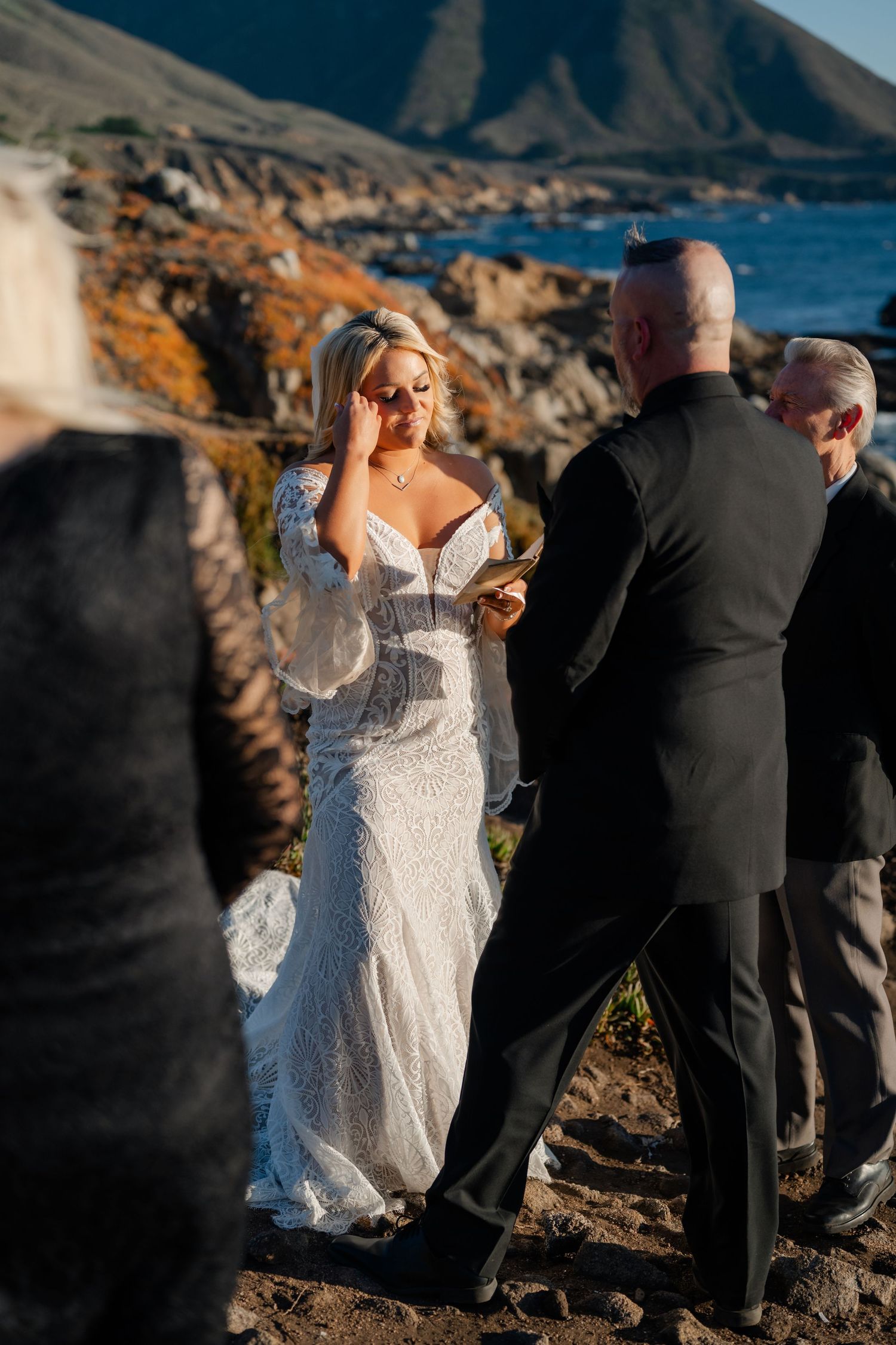 A coastal wedding ceremony unfolds on a dramatic cliffside overlooking the Pacific Ocean.