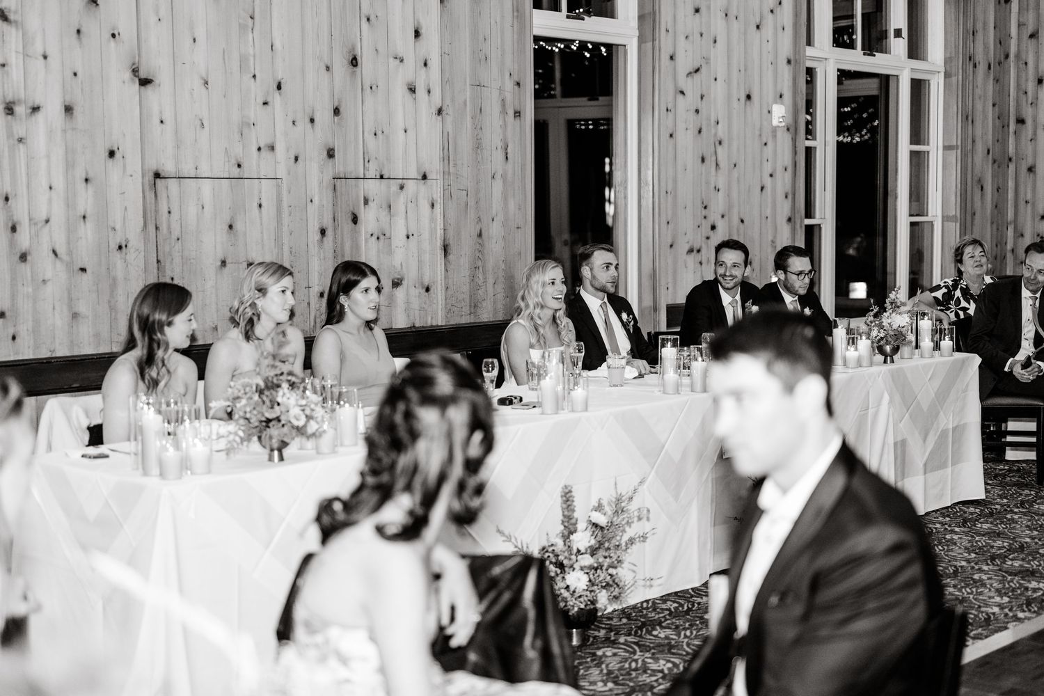 Black and white photo of elegant wedding reception tables set in a rustic wooden barn venue.