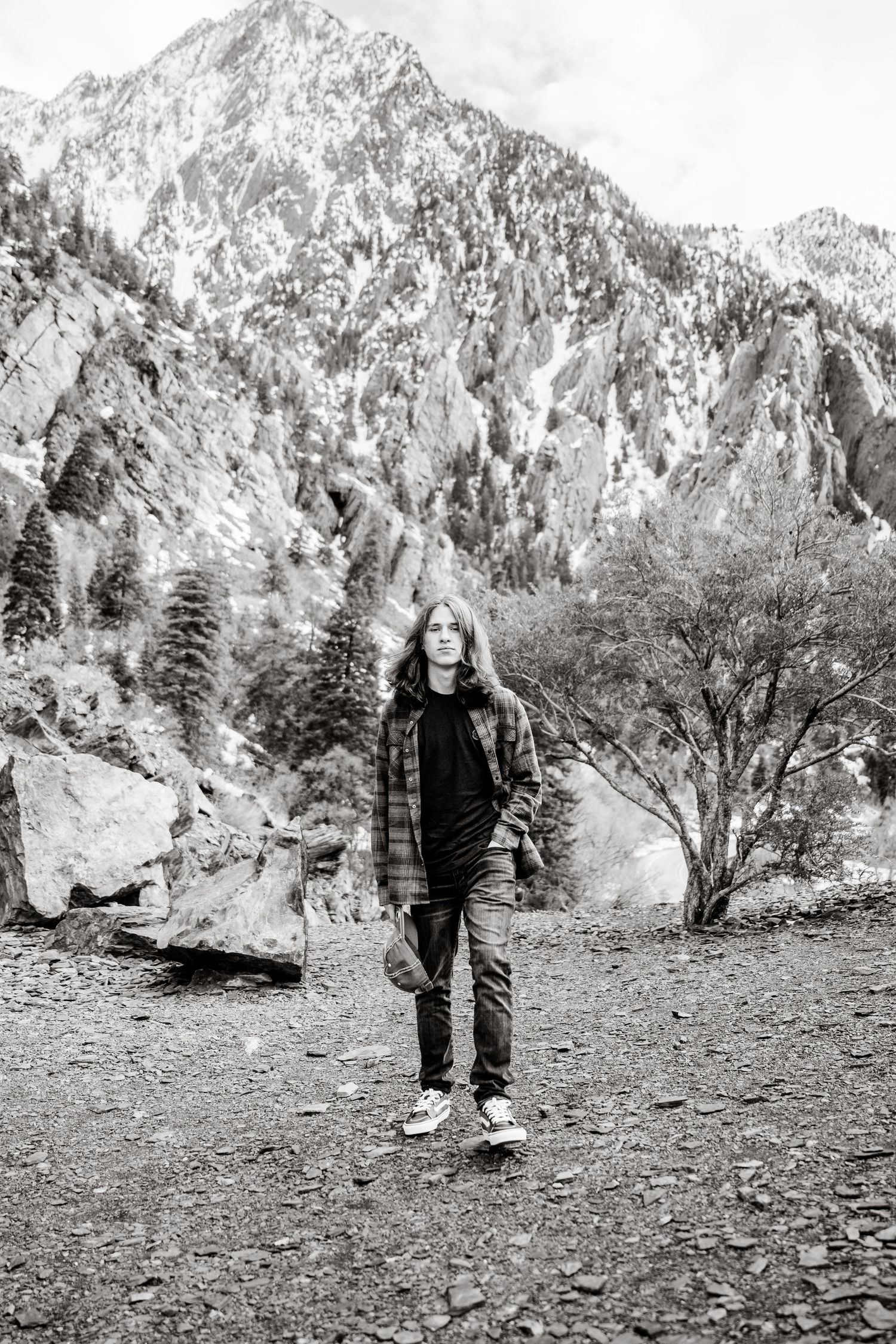A series of black and white photos showing someone standing in a rugged mountain landscape with evergreen trees.