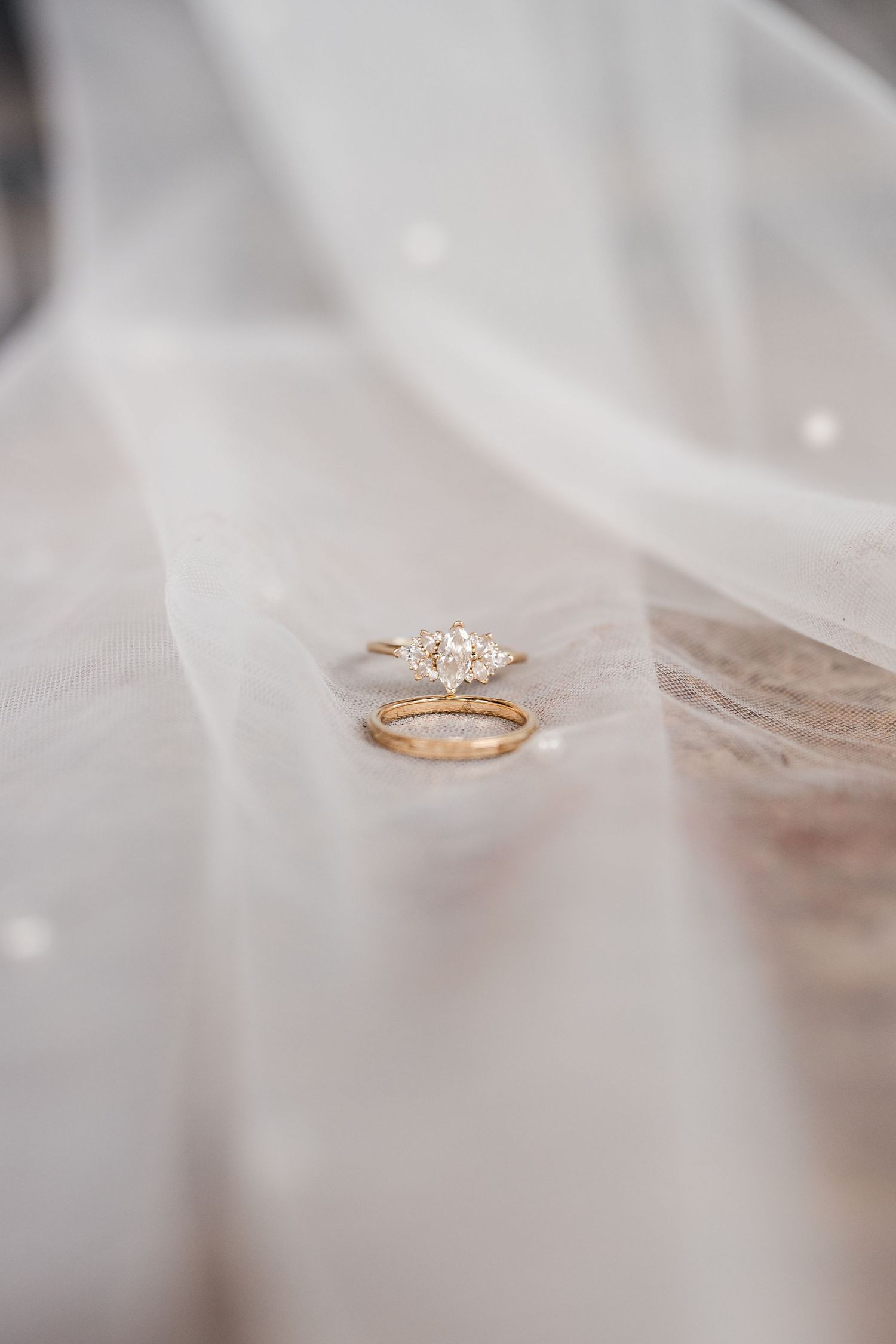 A delicate rose gold engagement ring with a solitaire diamond rests on a soft white fabric surface.