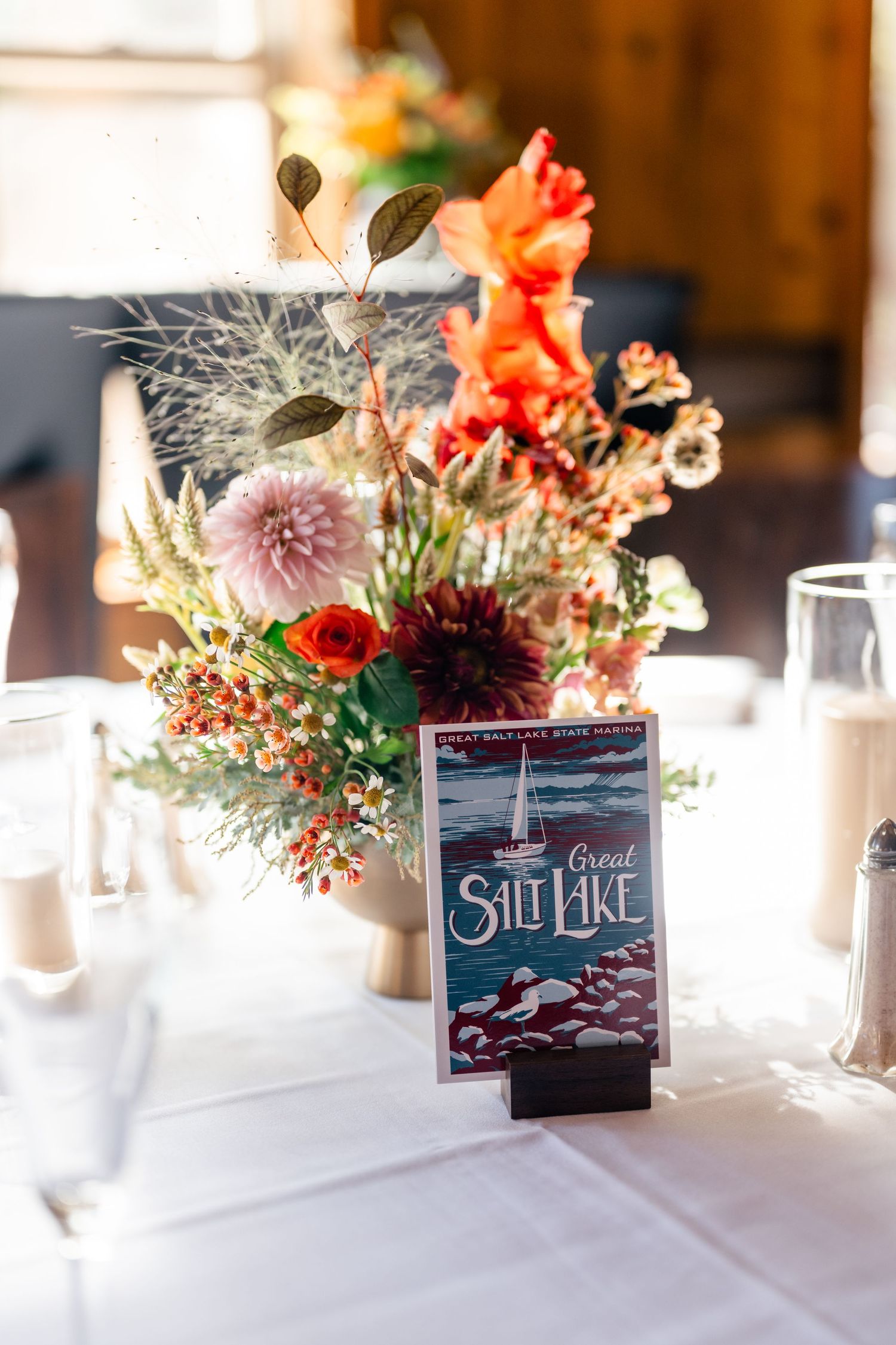 Elegant wedding table settings with floral centerpieces and decorative signs displaying table names.