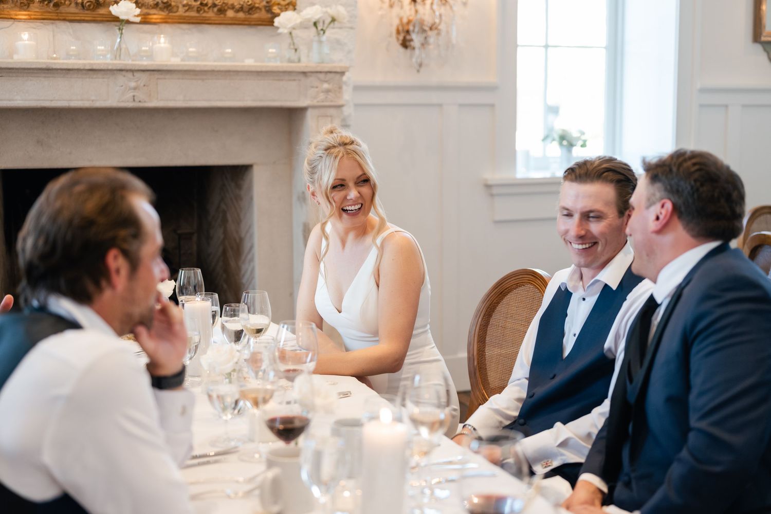 Elegant wedding reception table setting with crystal chandeliers and gold-framed mirrors.