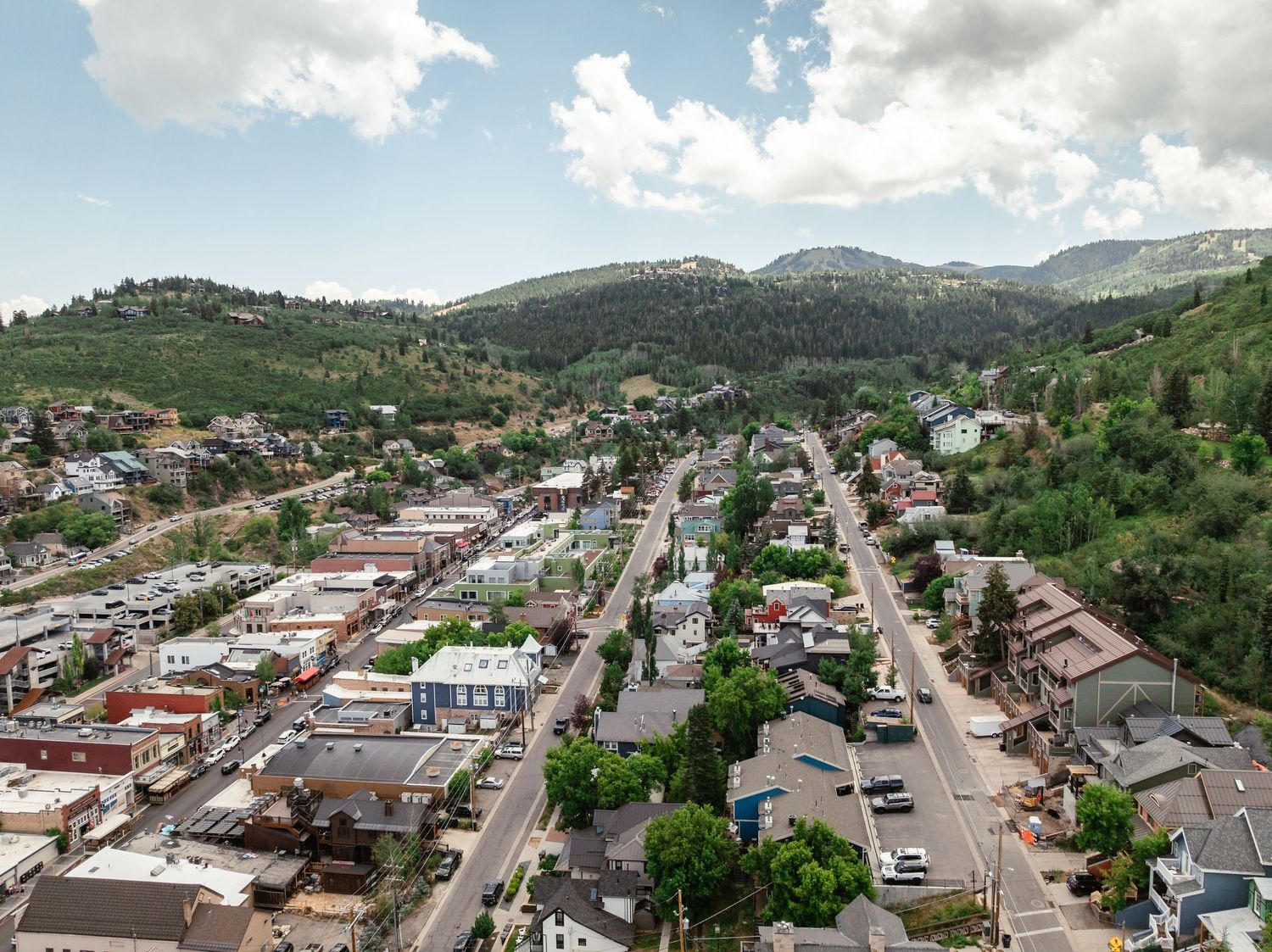 Aerial view of a small mountain town with buildings lining the main street and mountains in the background.