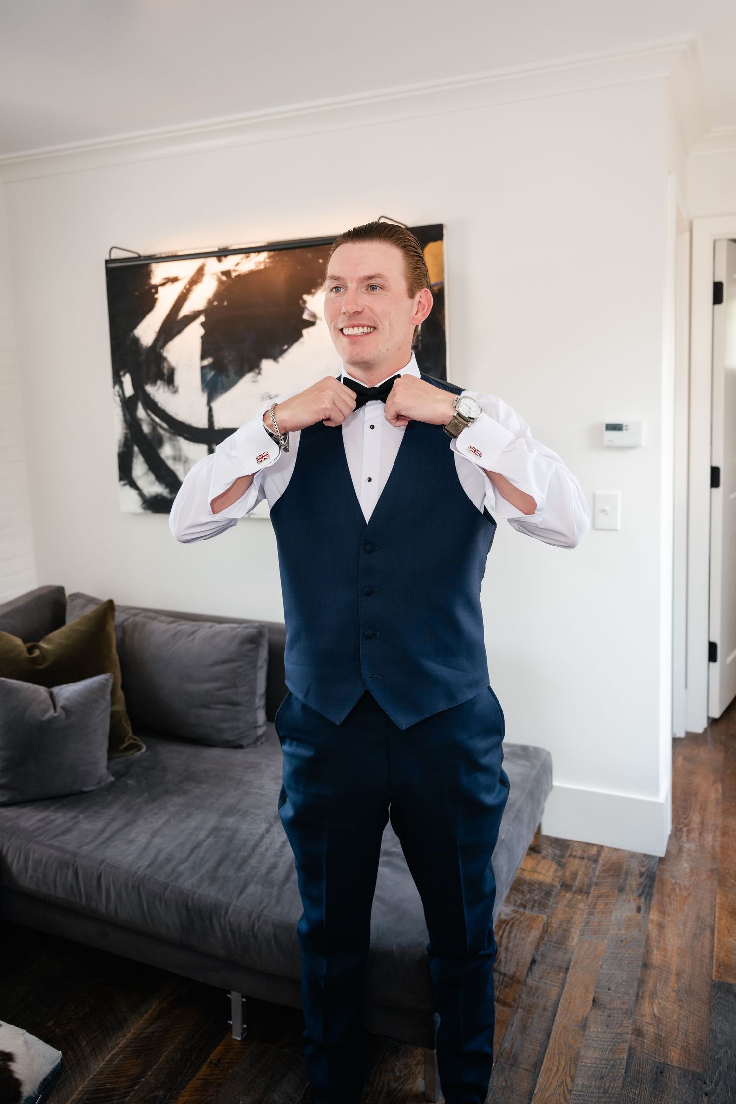 Person in navy formal attire making playful poses in modern living room.