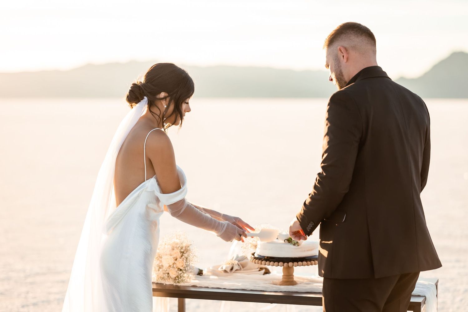 Wedding couple sharing playful moment on salt flats during sunset photoshoot.