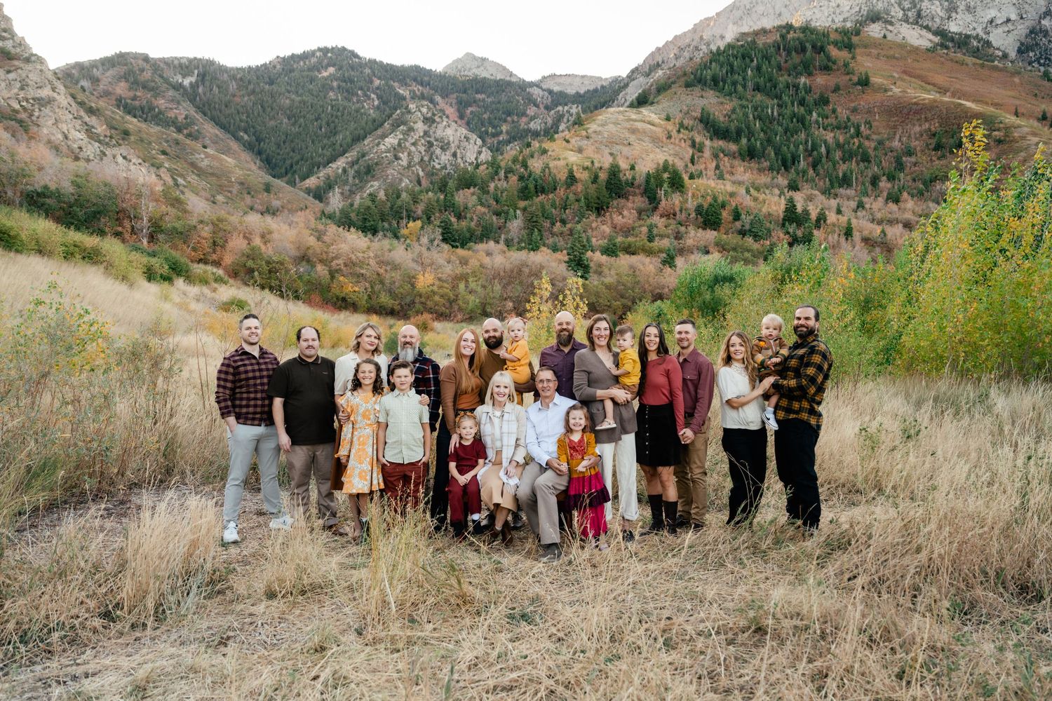A group of people standing together on a hillside path with mountains and autumn foliage in the background.