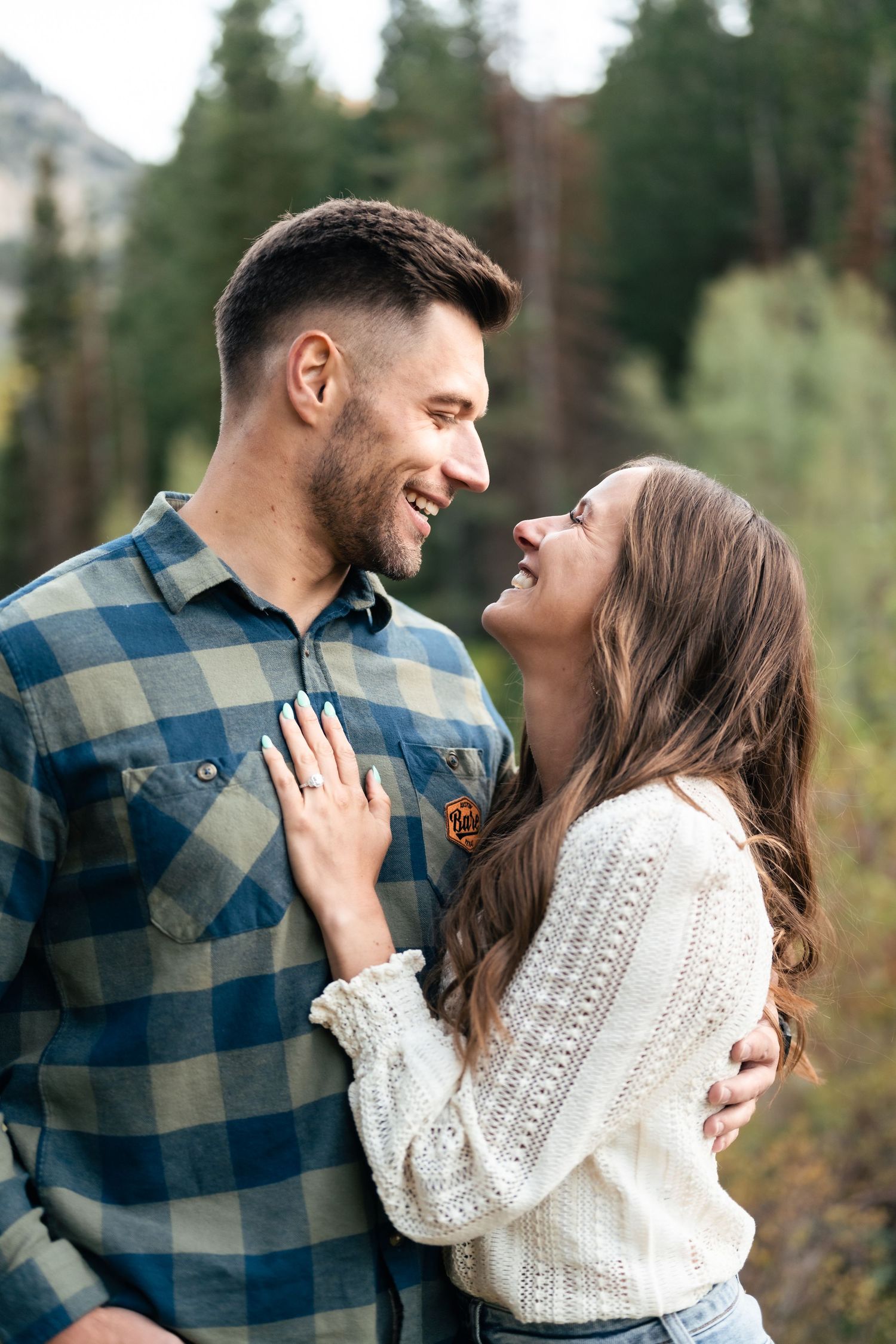 A joyful moment shared between a couple against a backdrop of mountain forest.