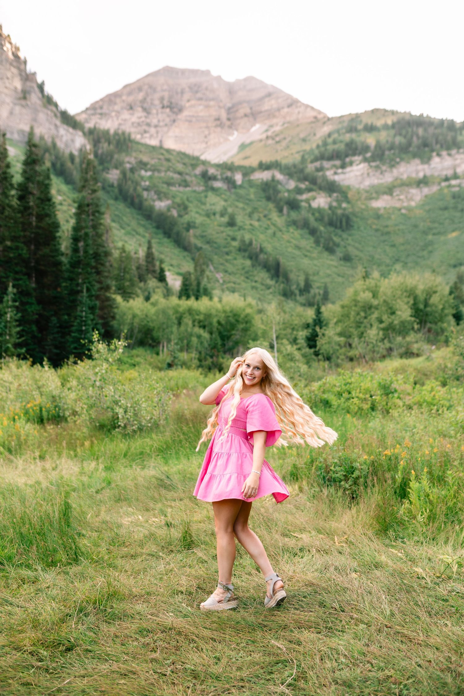 twirling in a hot pink dress in a mountain meadow during a senior session in american fork canyon