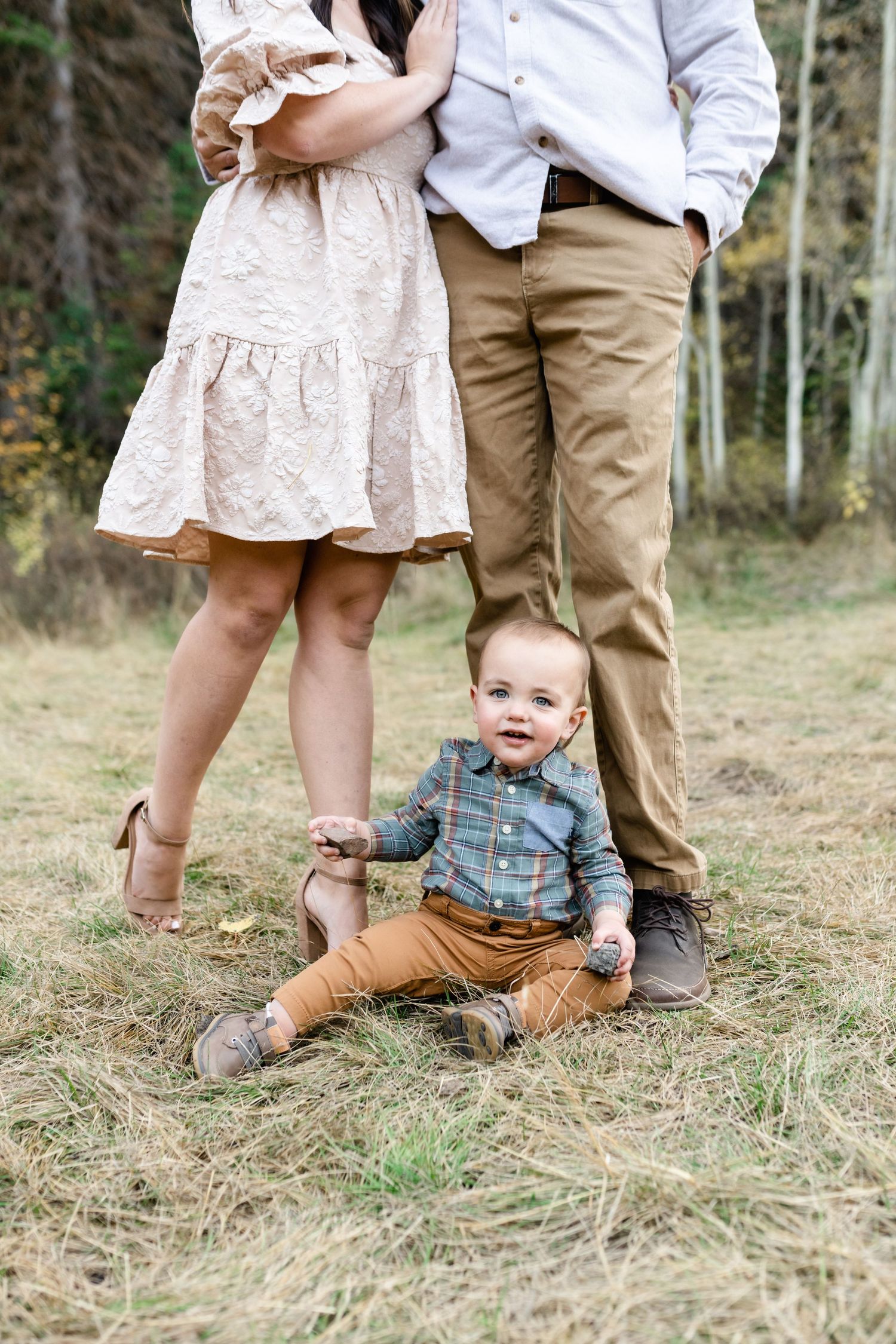 Family in coordinated casual outfits poses together in grassy field.