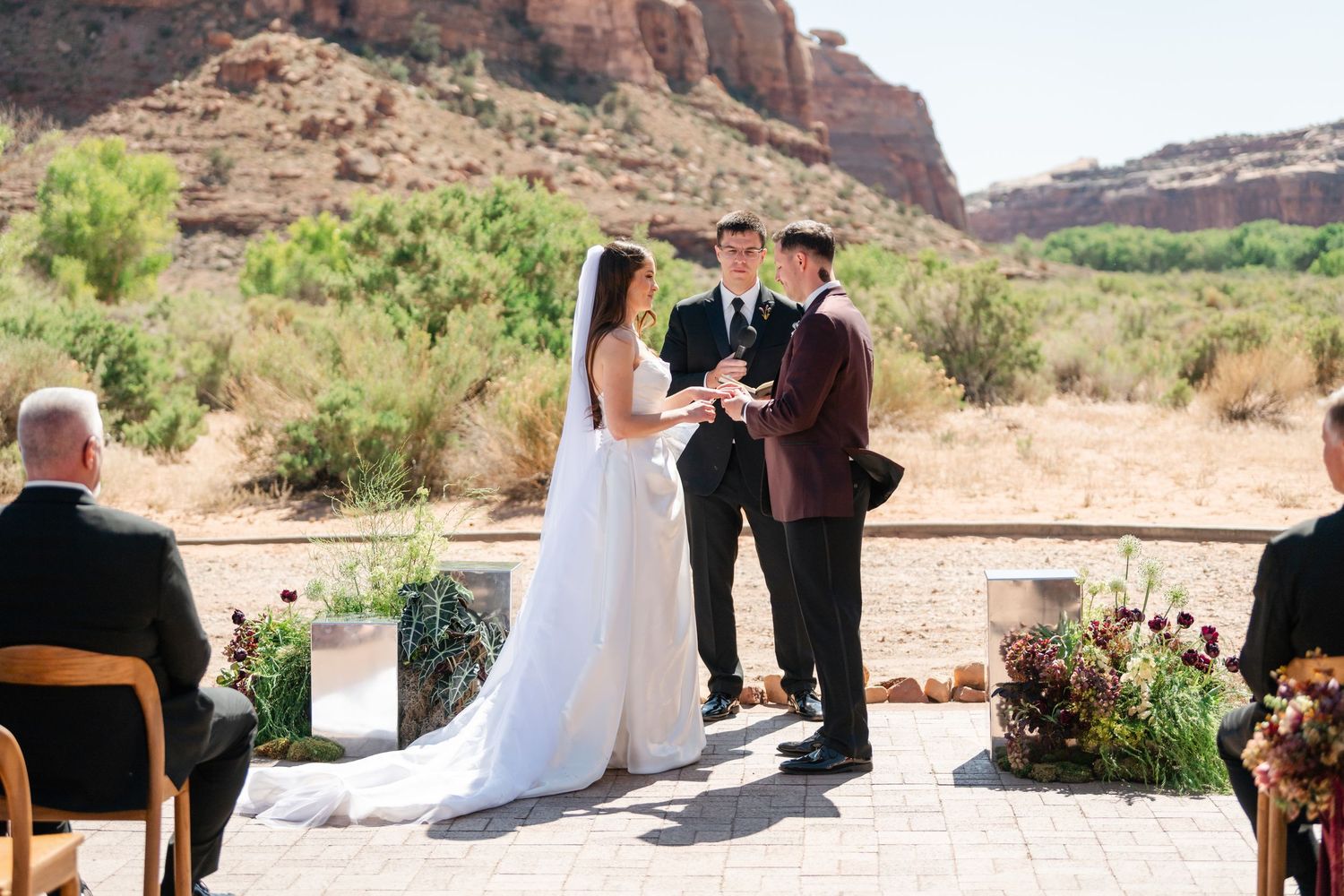 Outdoor desert wedding ceremony with couple exchanging vows before red rock canyon backdrop in Moab, Utah.