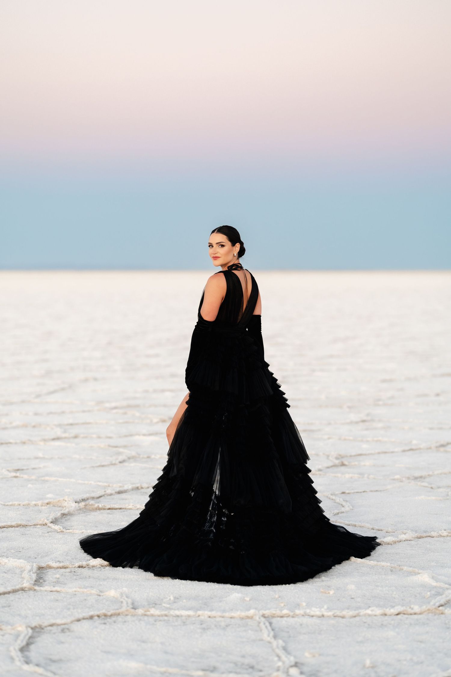Utah Salt Flats Photographer. A dramatic black gown flows across the white salt flats during a sunset photoshoot.
