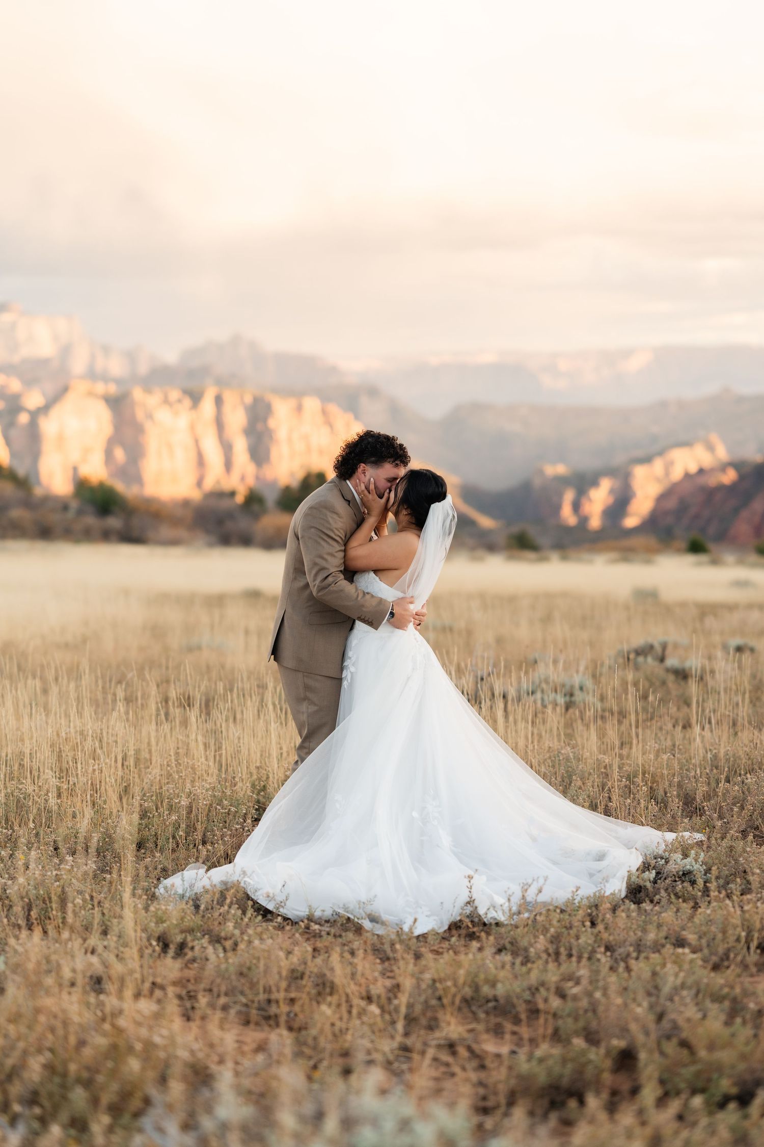 A romantic wedding photo sequence in a field with mountains and golden light.