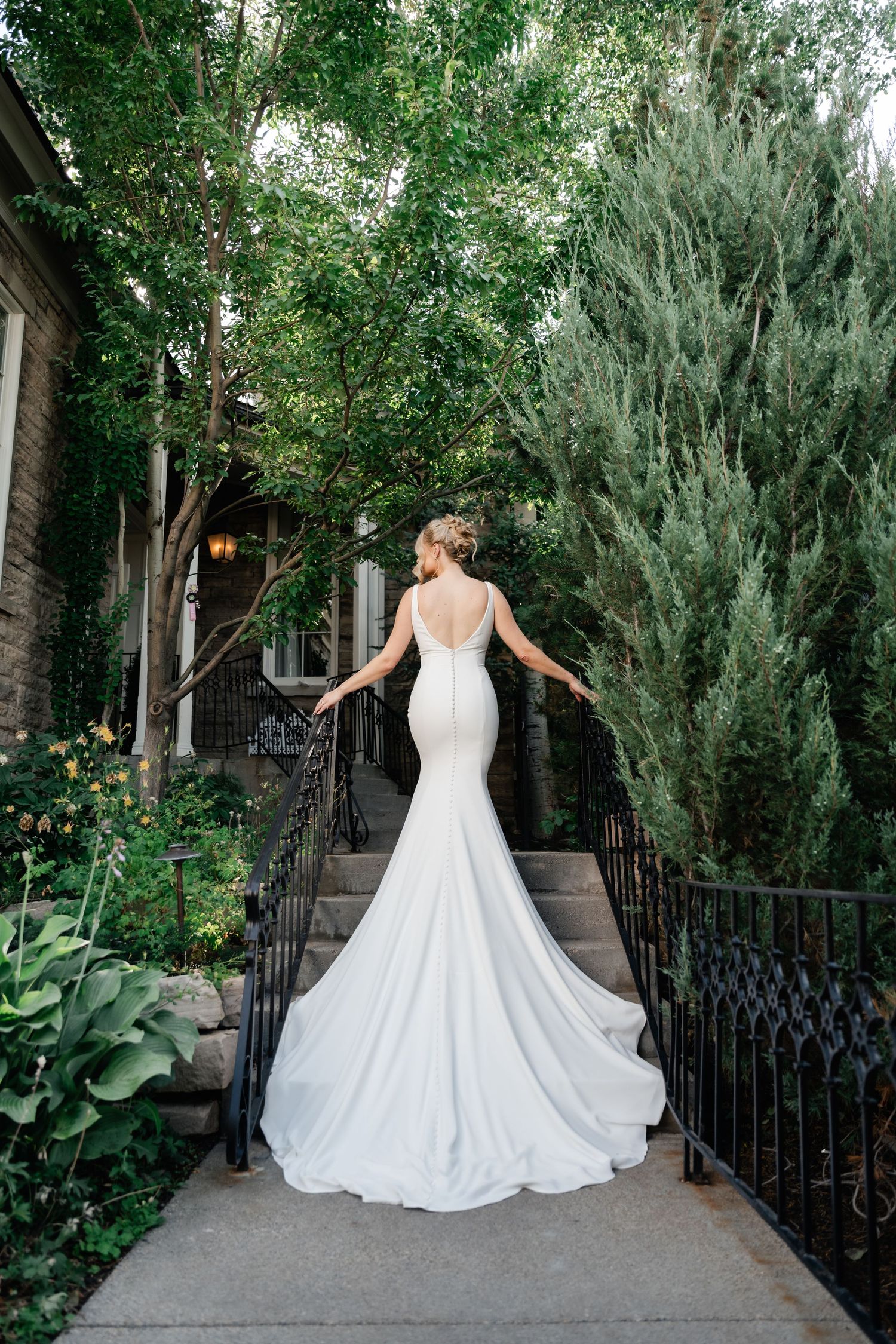 Stunning mermaid wedding gown with dramatic train photographed in a garden setting.