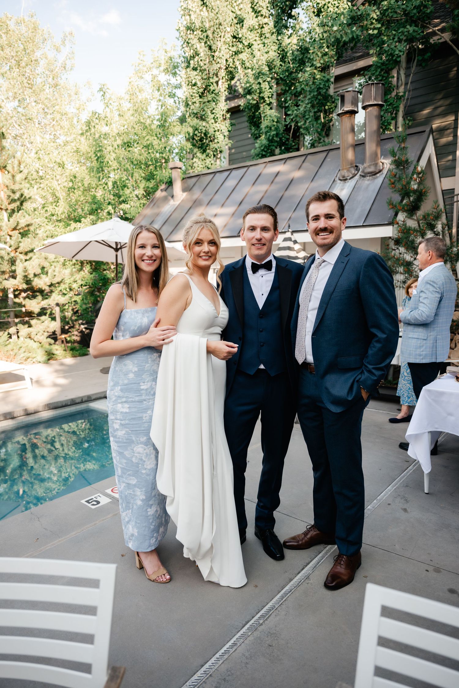 Wedding celebration on outdoor patio with pool and natural landscaping in background.