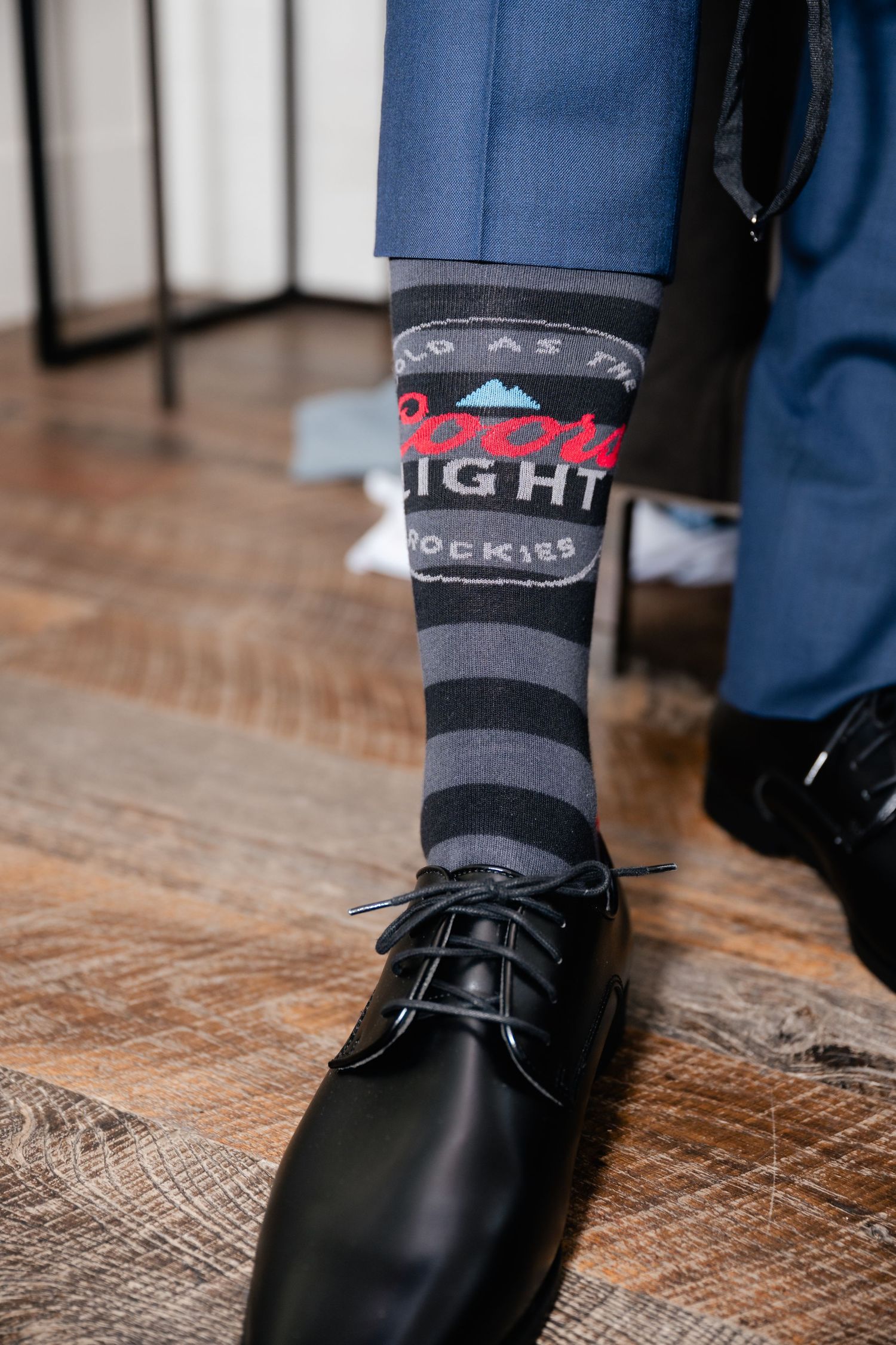 Close-up of dress shoes and fun novelty socks on hardwood floor.