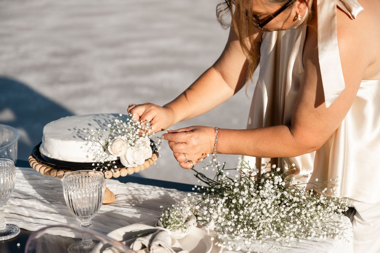 Hands arranging white baby's breath flowers on a table.