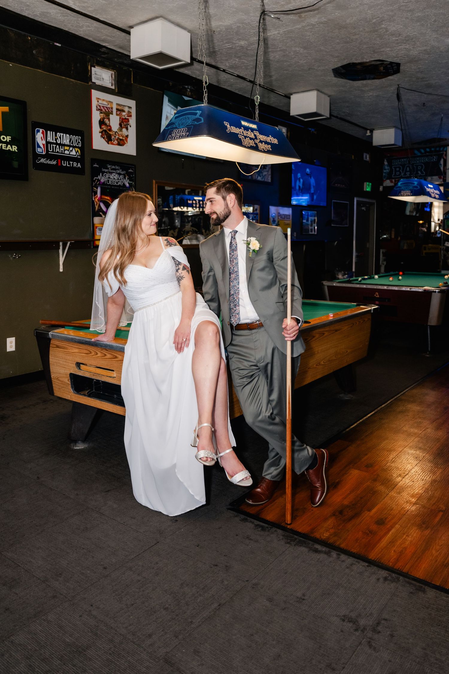 A couple shares an intimate moment against a pool table in a casual bar environment.