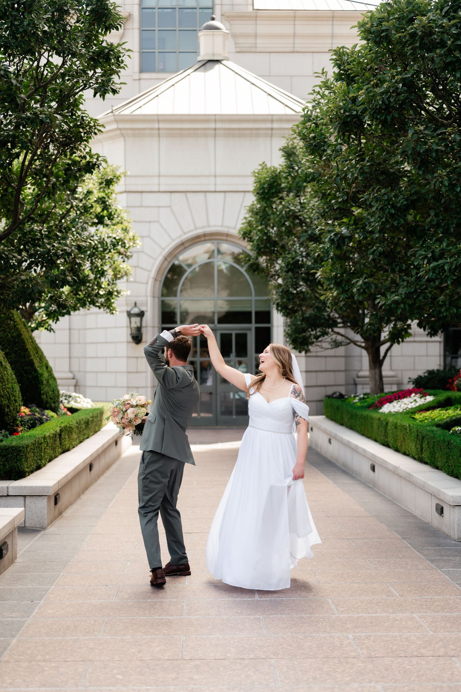 A series of wedding photos showing a couple dancing and twirling on a stone patio surrounded by greenery and architecture.
