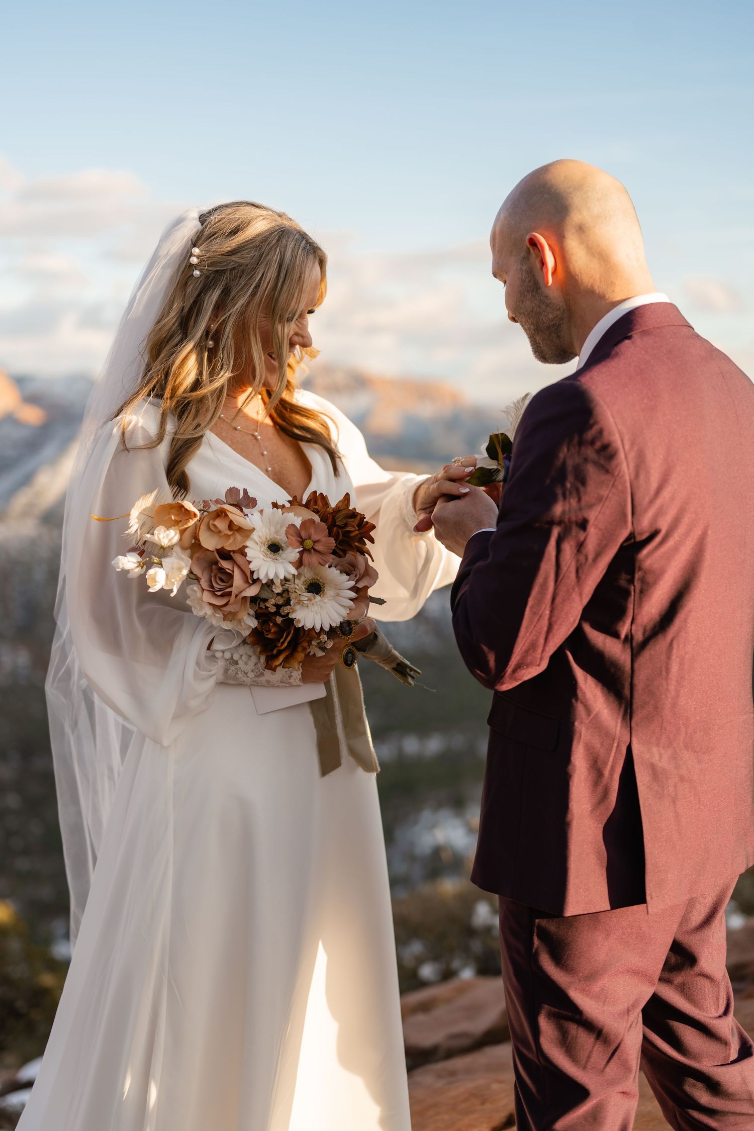 Wedding couple sharing intimate moment against backdrop of desert cliffs at sunset.