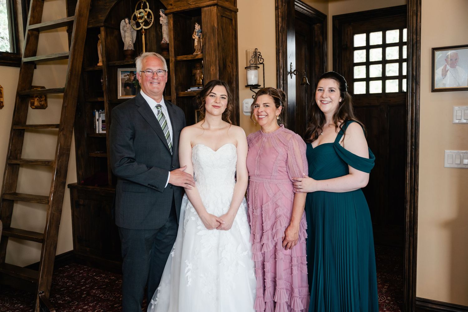 Wedding party poses together in formal attire inside rustic venue.