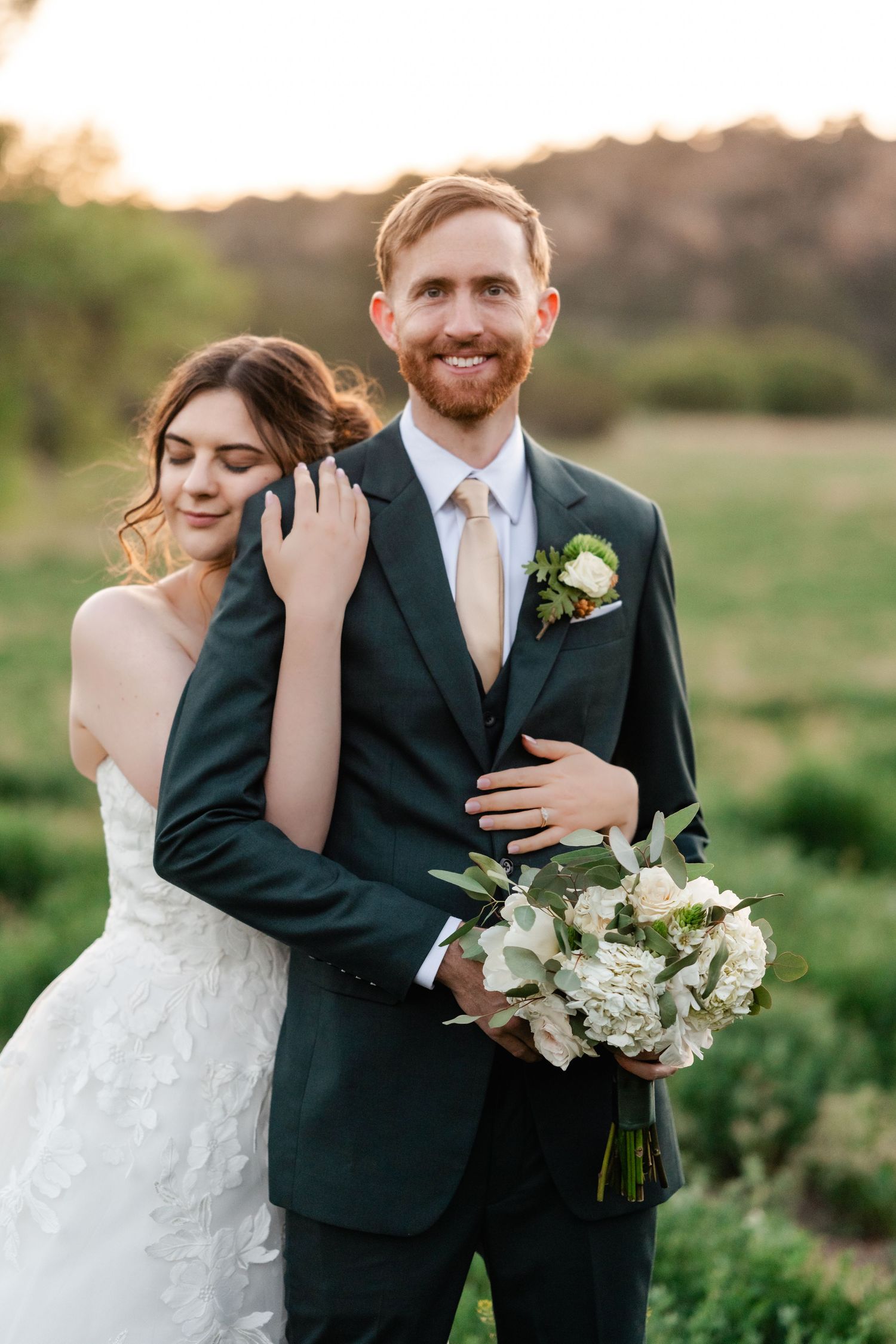 Intimate wedding portrait in a lush green field during golden hour.