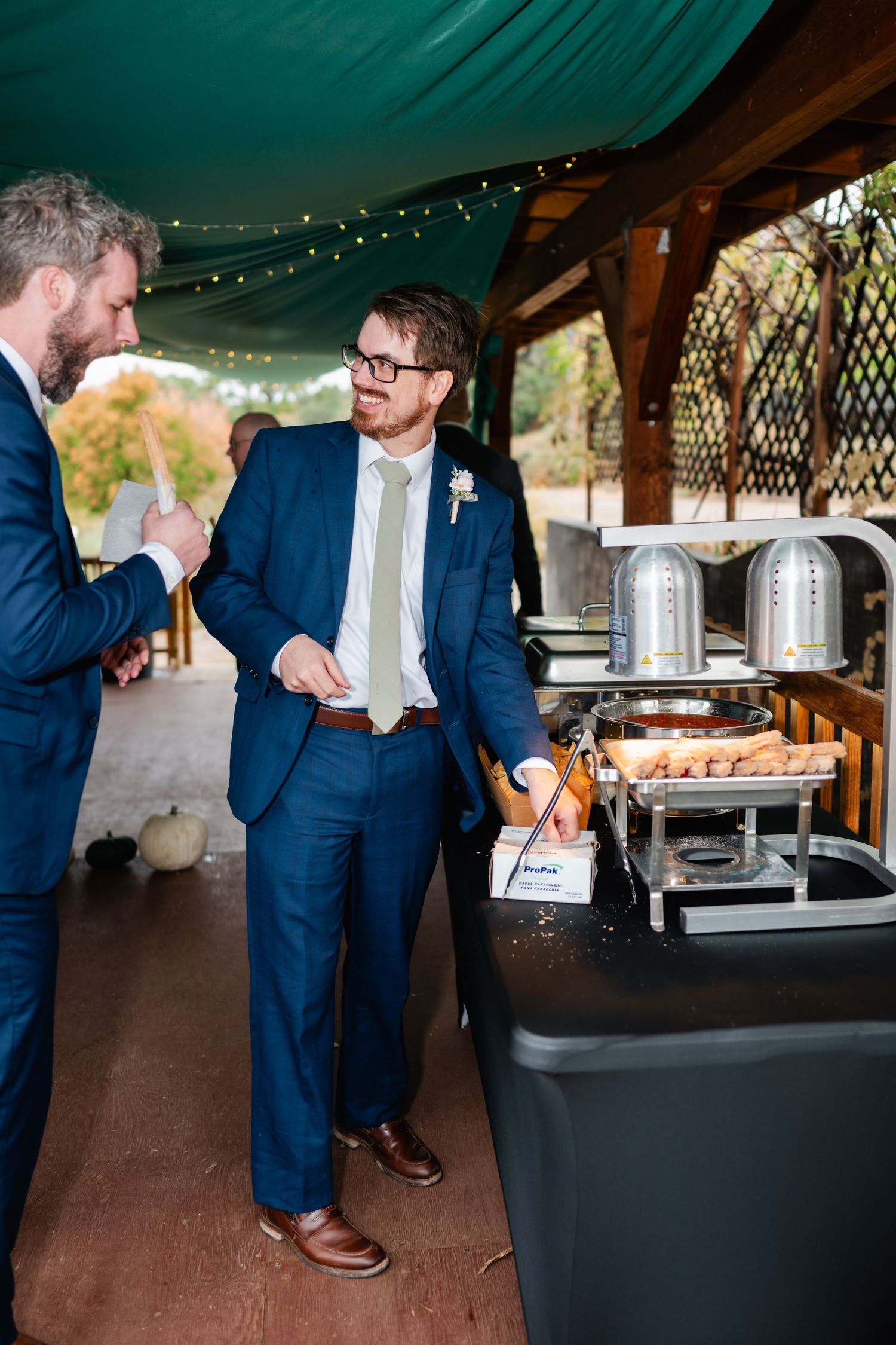 Buffet service setup with chafing dishes under a covered outdoor pavilion.