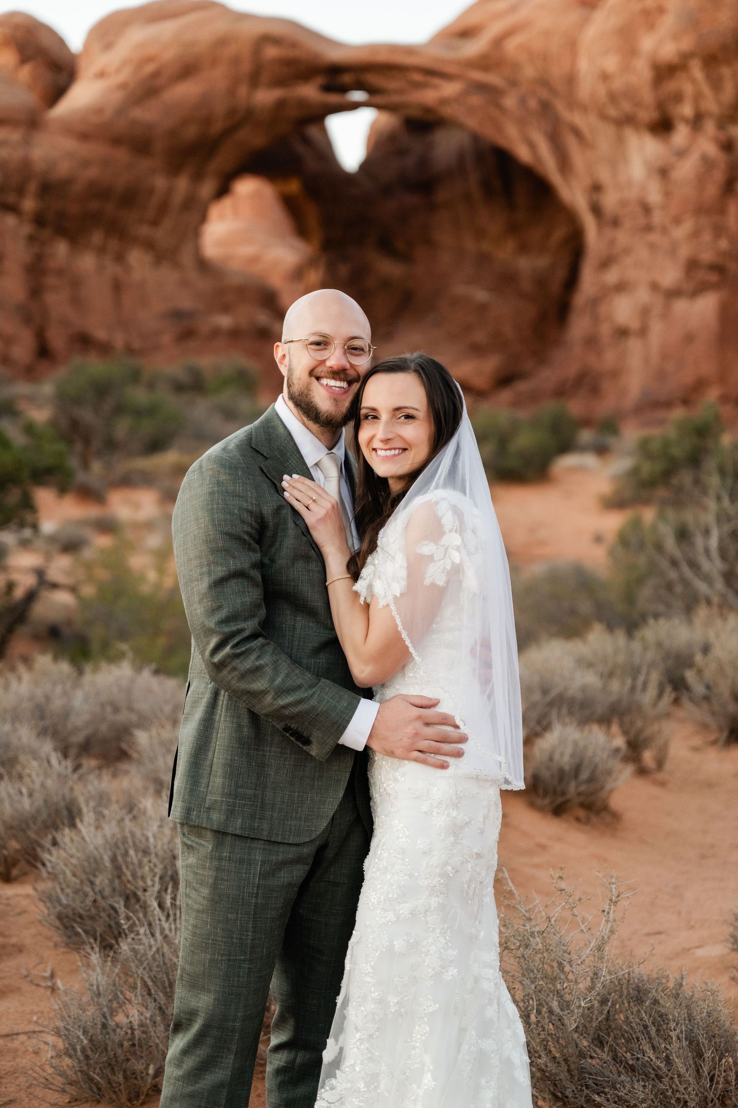 Intimate wedding moment captured against stunning desert rock formations at sunset.