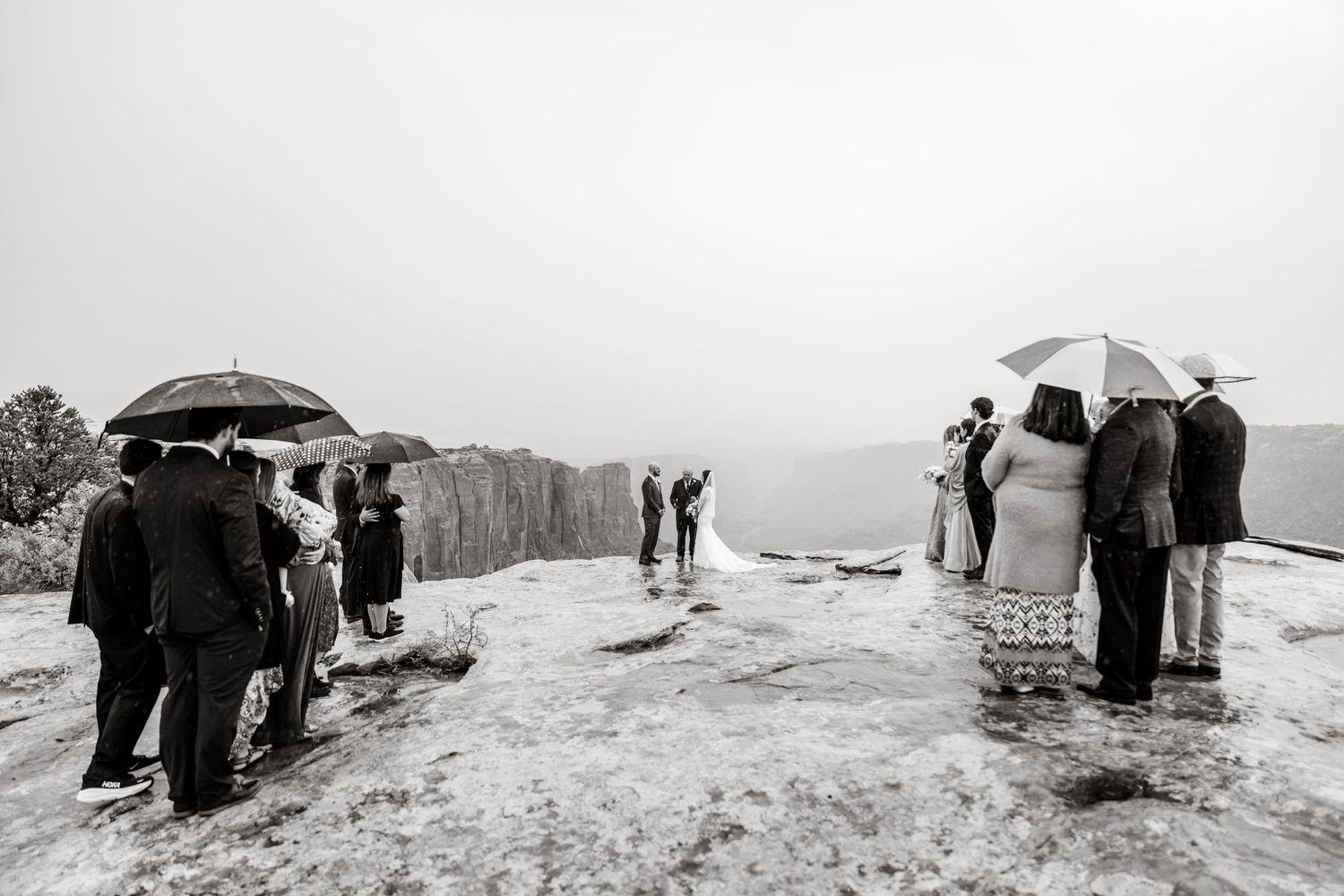 Black and white panoramic shots of wedding guests gathered on a cliff edge.