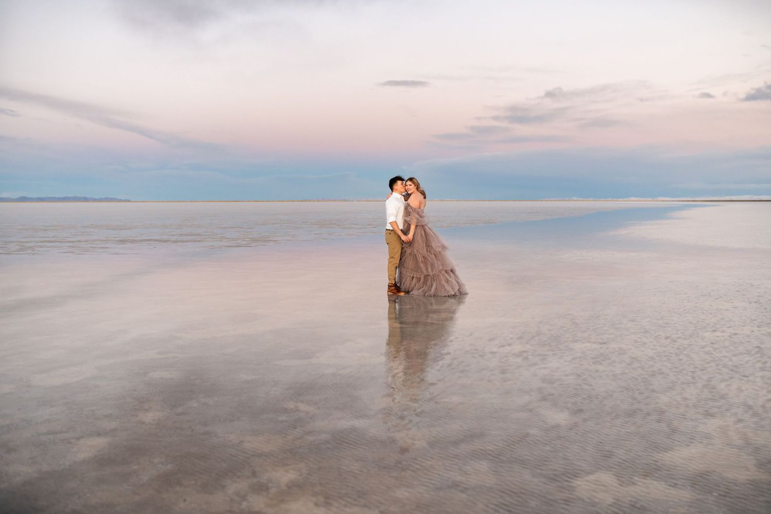 Wedding photo at dusk on the Bonneville Salt Flats with reflective water and pastel sky.
